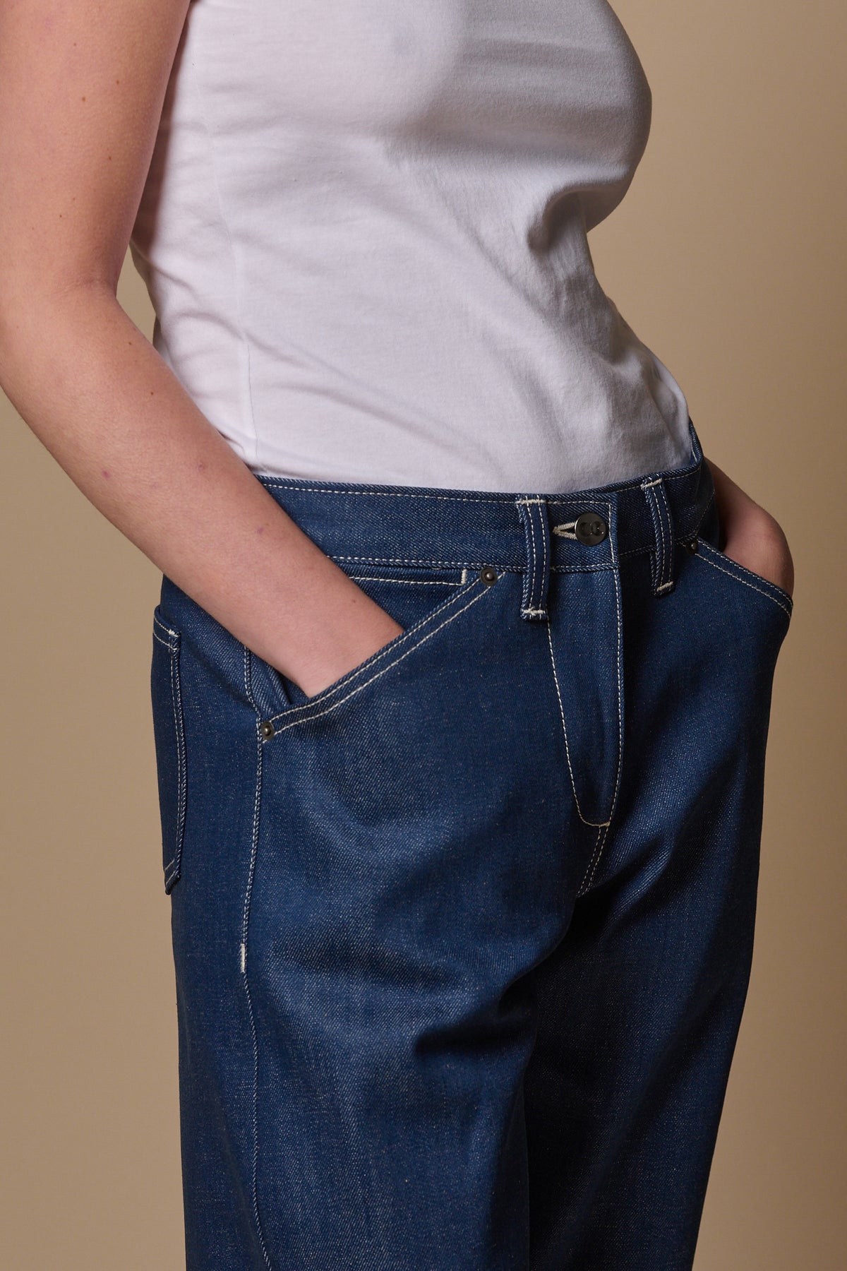 
            Female with hands in the two front pockets of chore jeans in blue. Coin pocket, front belt loops and CC logo on front button fastening 