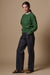 Full body image of the side of female wearing chore jeans in indigo with one hand in pocket. Worn with raglan sweatshirt in bottle green