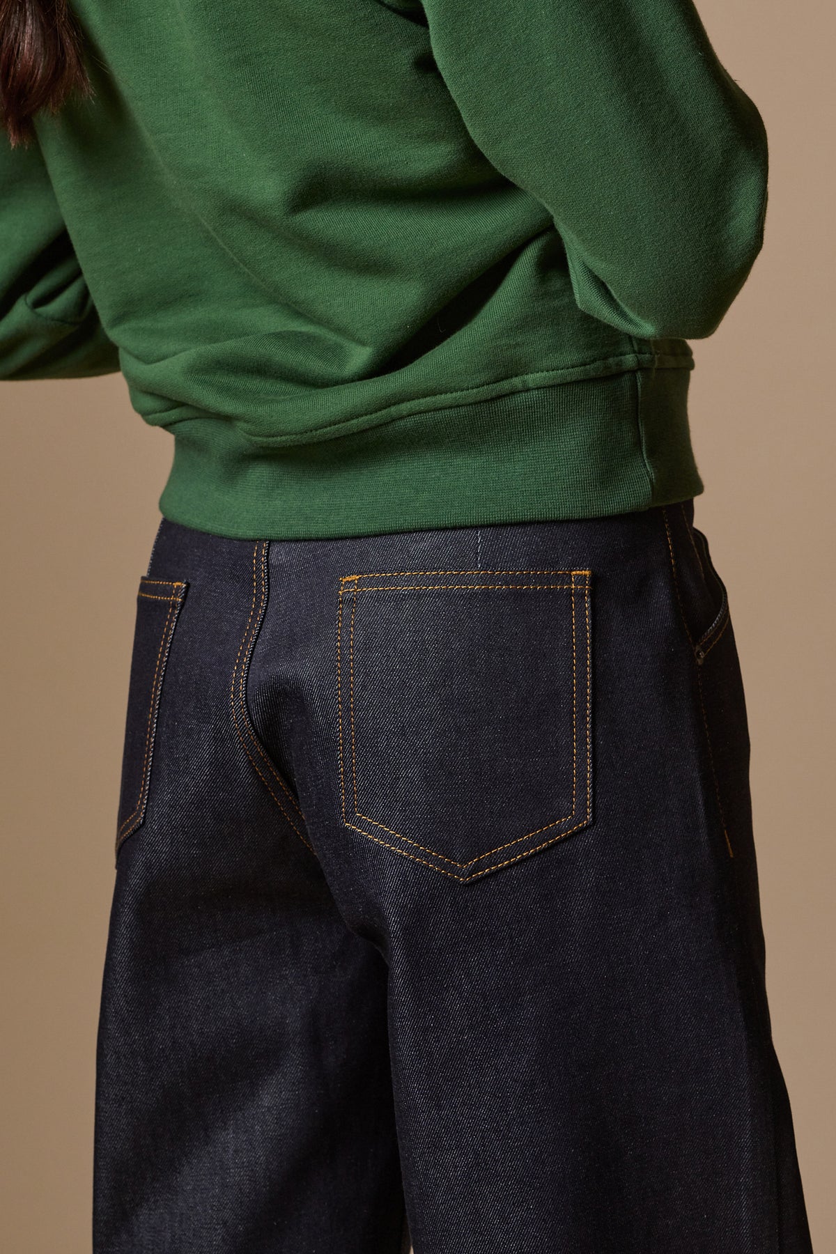 
            Back pocket details of chore jeans in indigo with orange stitching.
