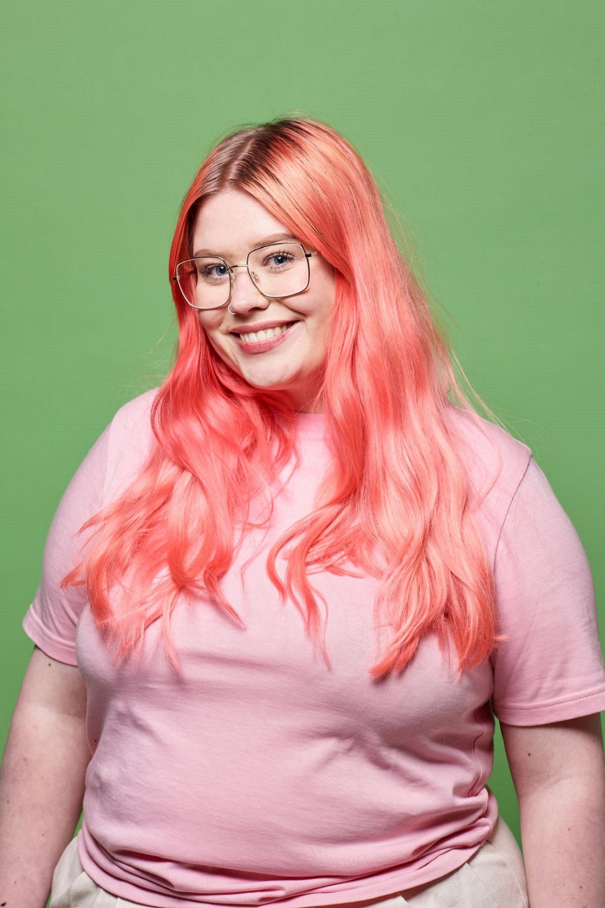 
            White female with pink hair, glasses and wearing a pale pink short sleeve Community Clothing T-shirt