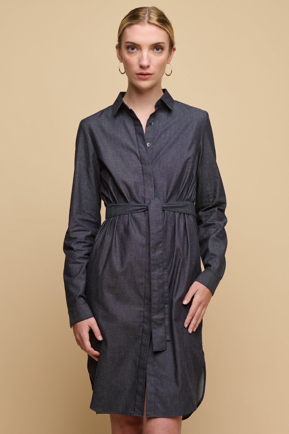 
            Knee up image of female wearing collared shirt dress in indigo with waist belt tied.