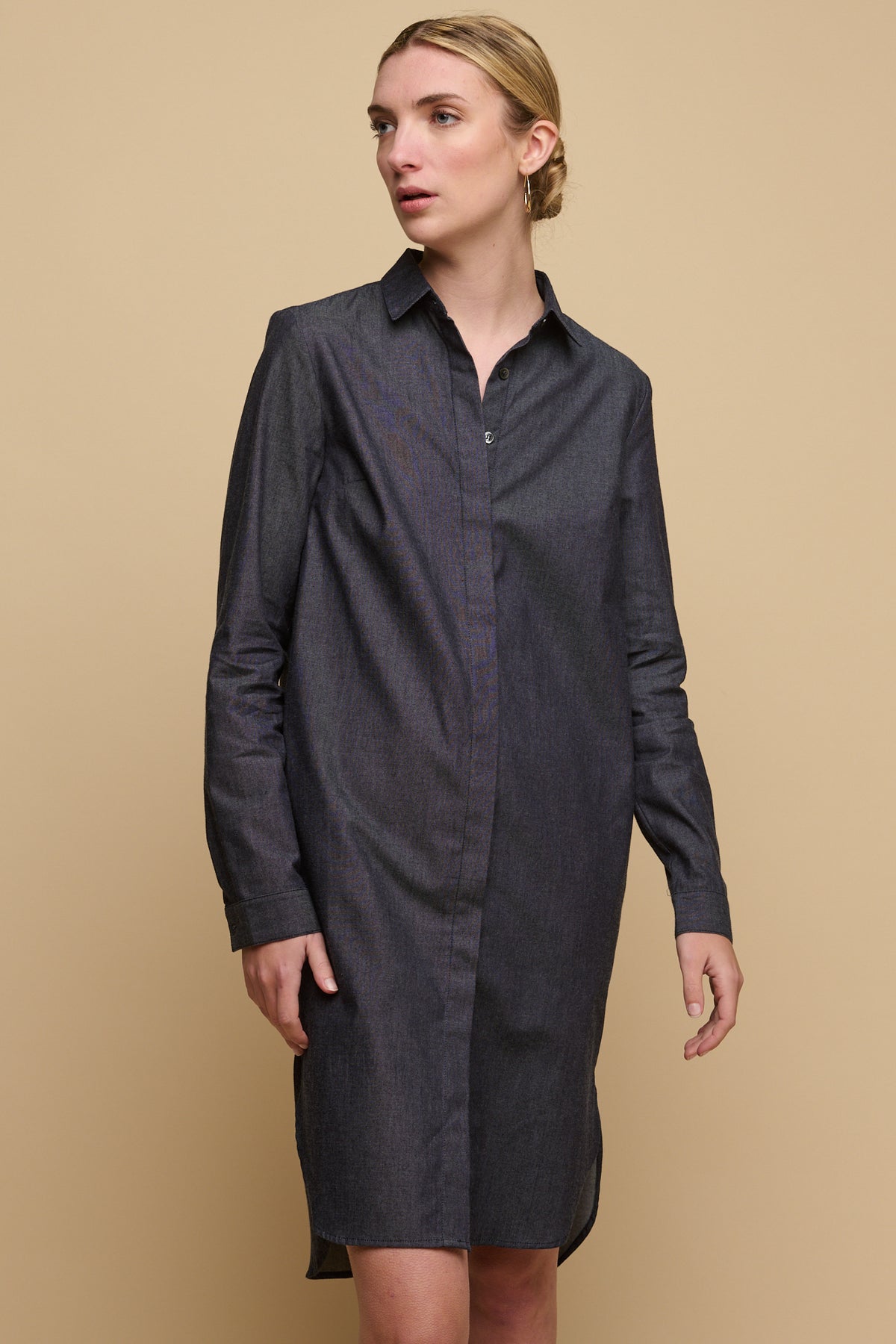 
            Knee up image of female wearing collared shirt dress in indigo with top three buttoned undone. 