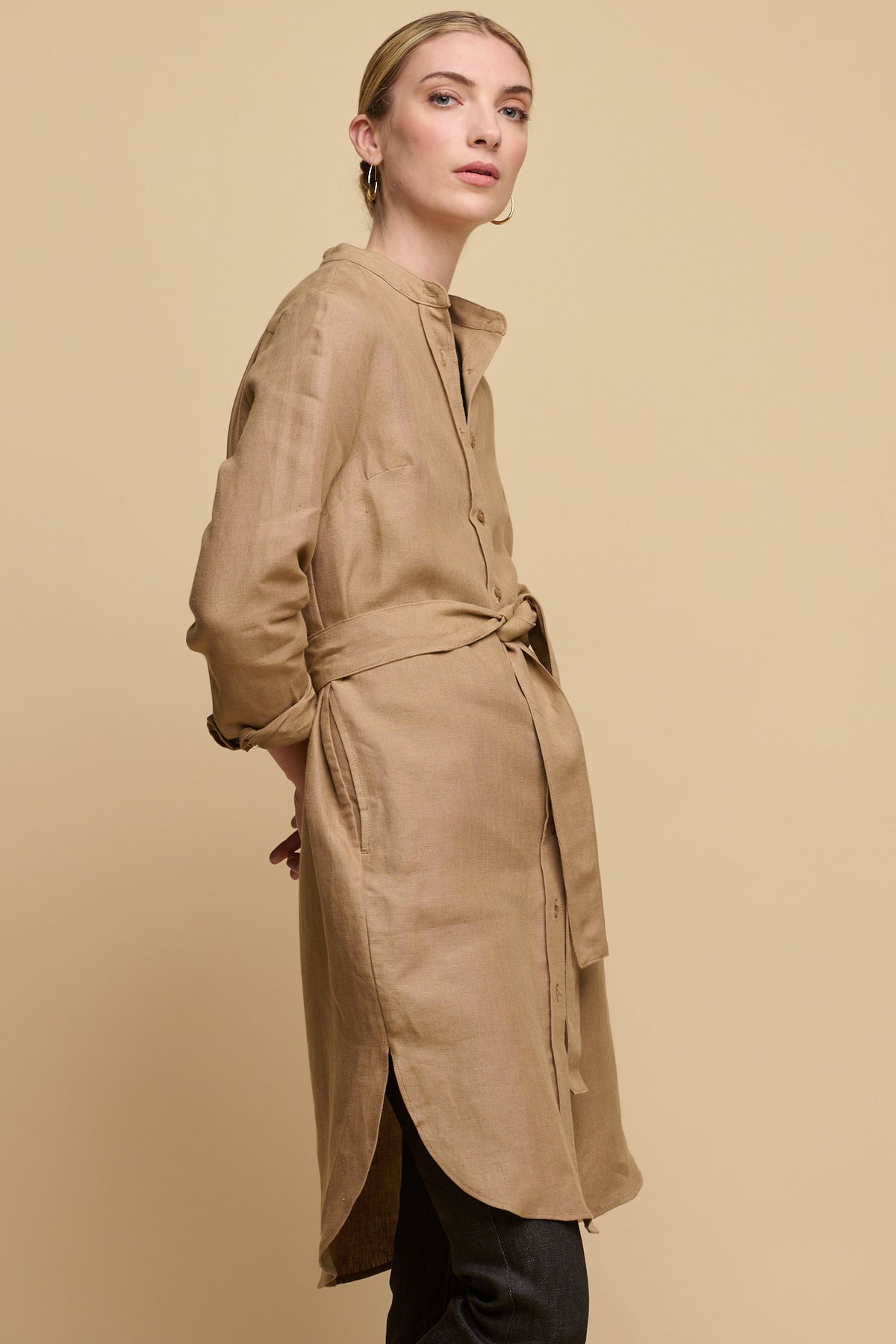 Female wearing collarless shirt dress with waist belt tie over women's straight leg jeans