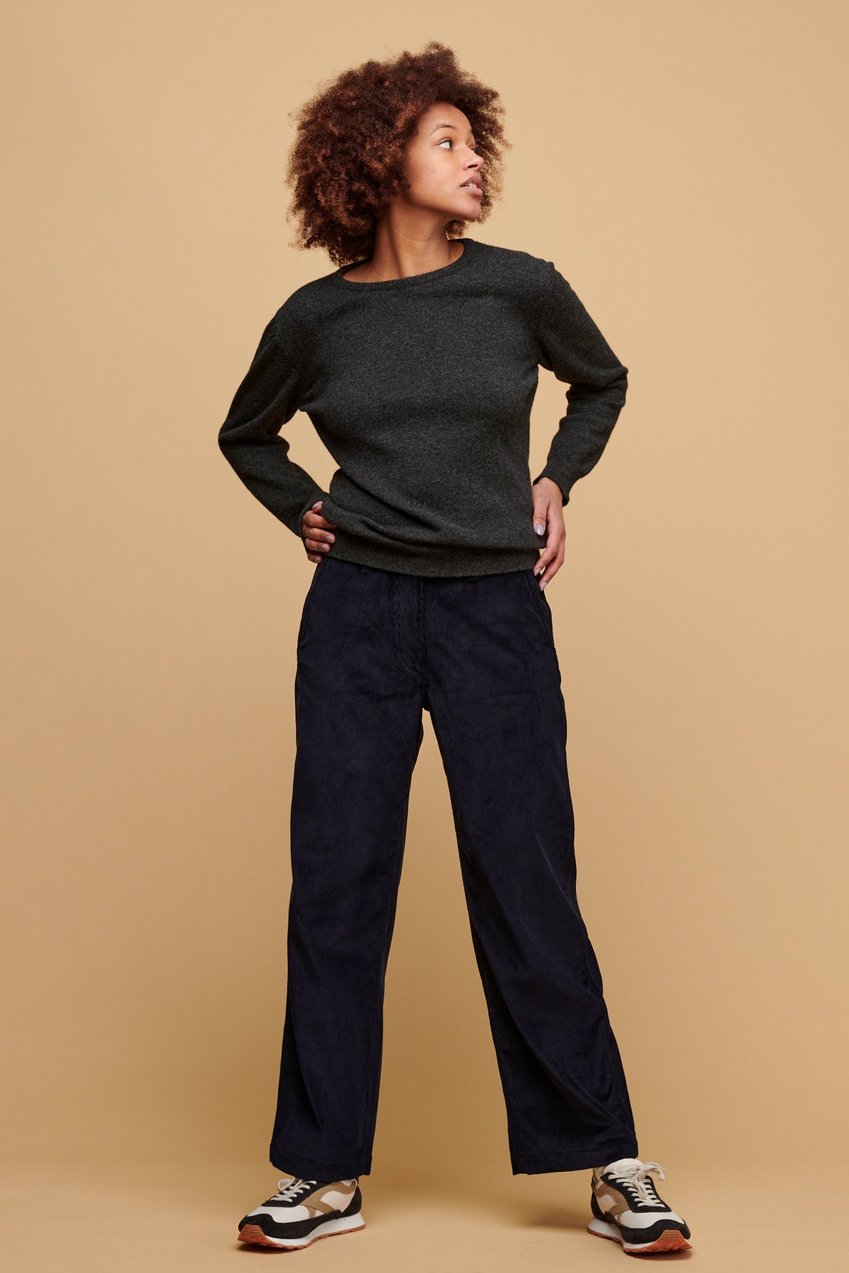 Female looking to the side wearing women's corduroy work trousers in navy, paired with lambswool crew neck in charcoal.