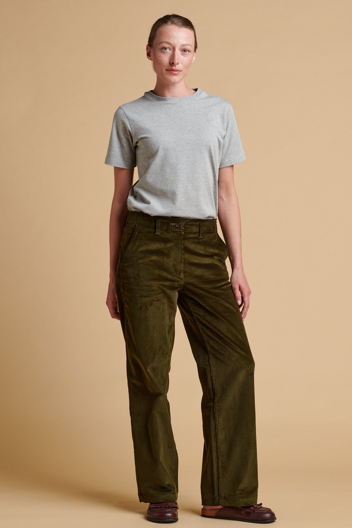 Female wearing corduroy work trousers in olive paired with short sleeve t shirt in grey marl.