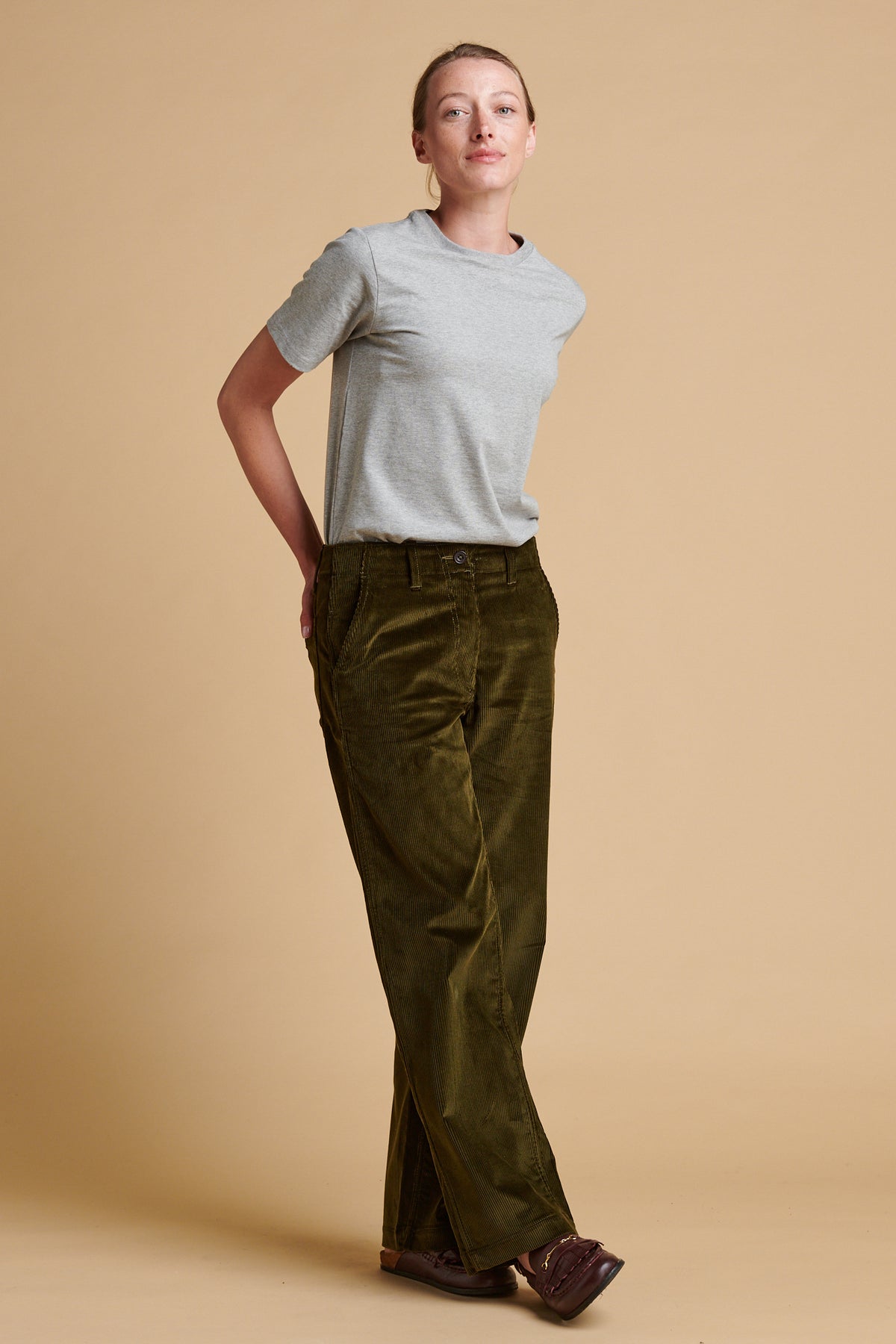 Female wearing corduroy work trousers in olive paired with short sleeve t shirt in grey marl.