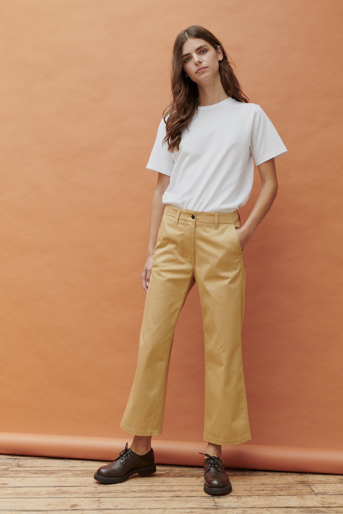 Front, full body image of brunette female wearing cropped work trousers in beige