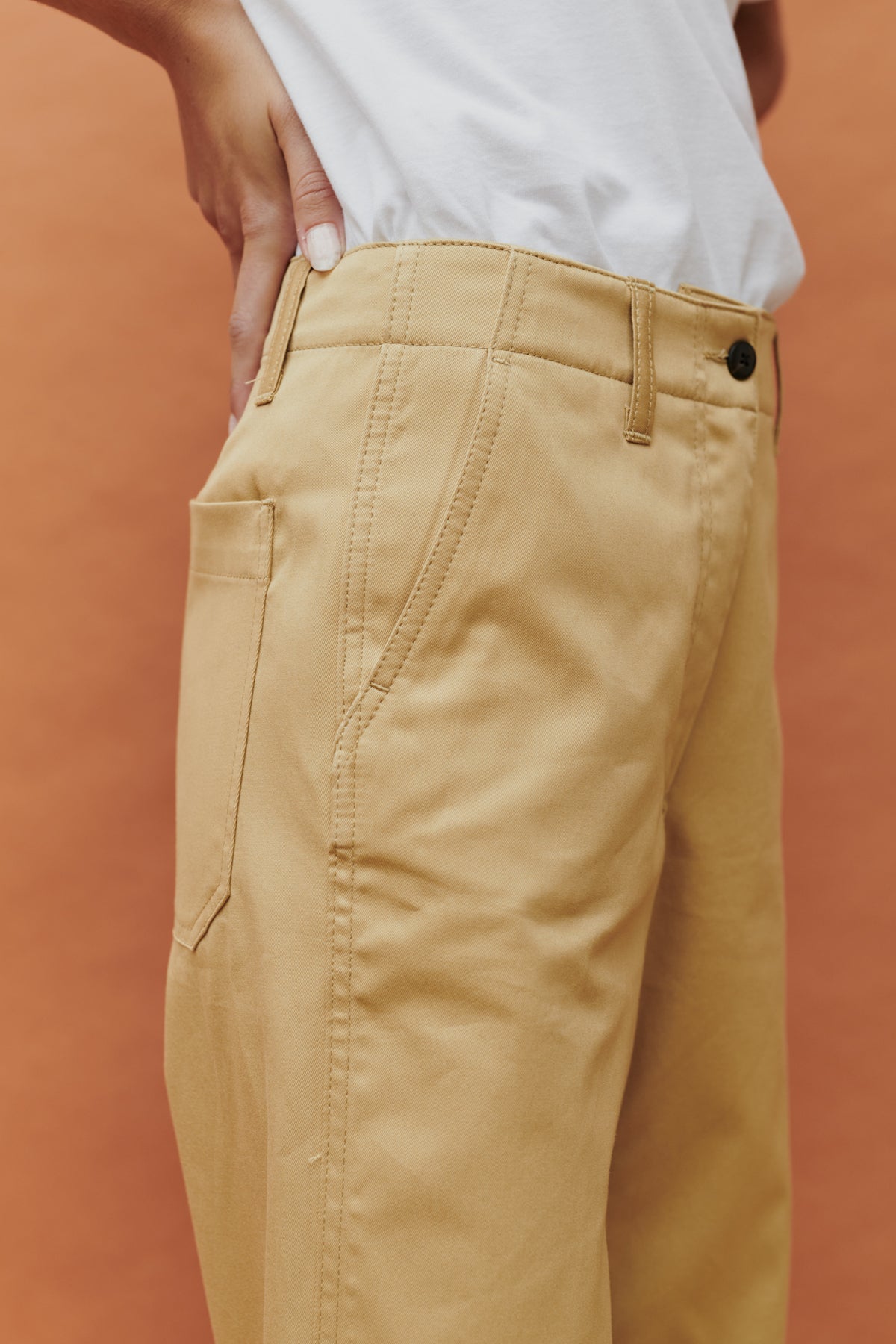 Front pocket and belt loop detail of female wearing cropped work trousers in beige