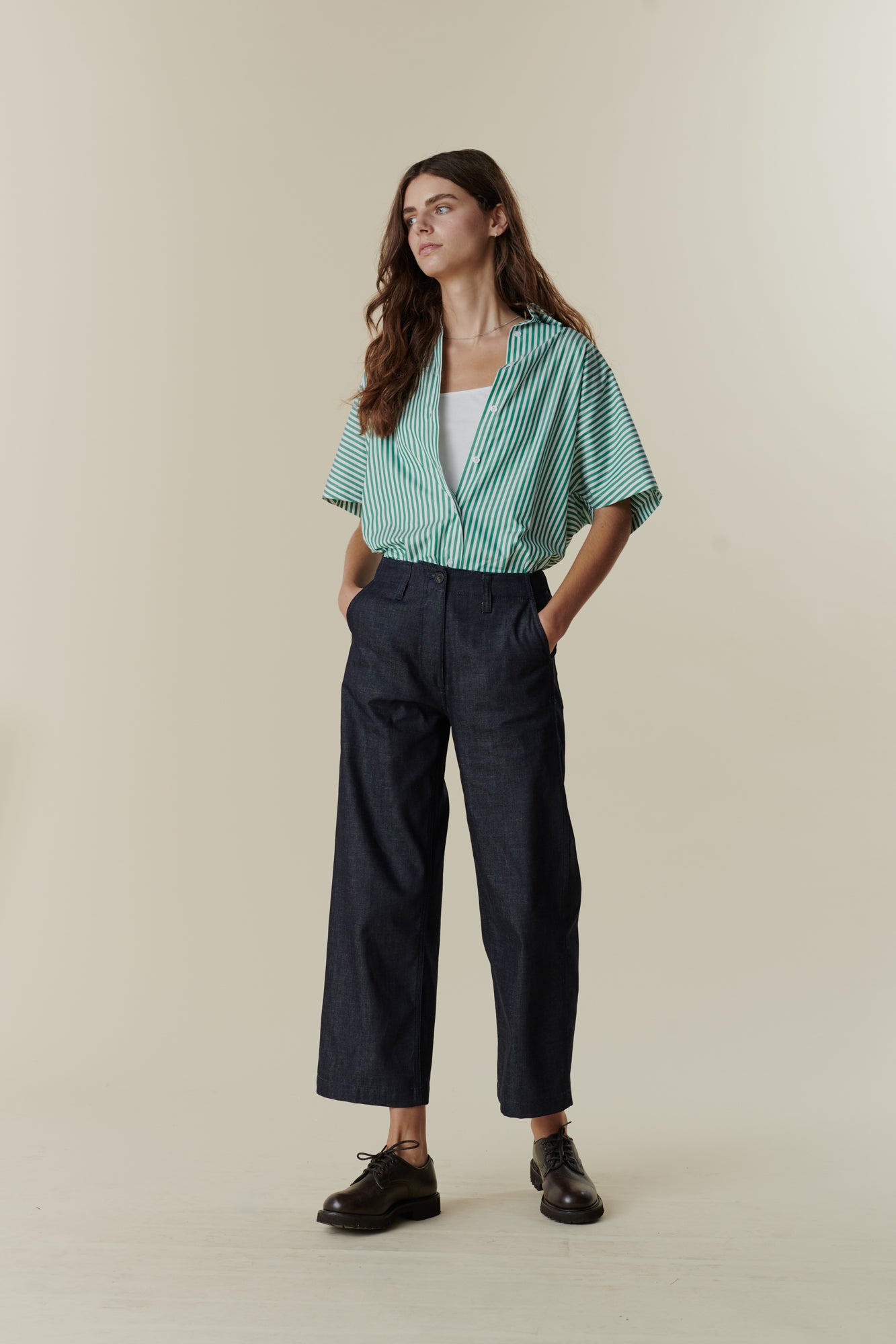 Full body image of female wearing cropped work trousers in denim 