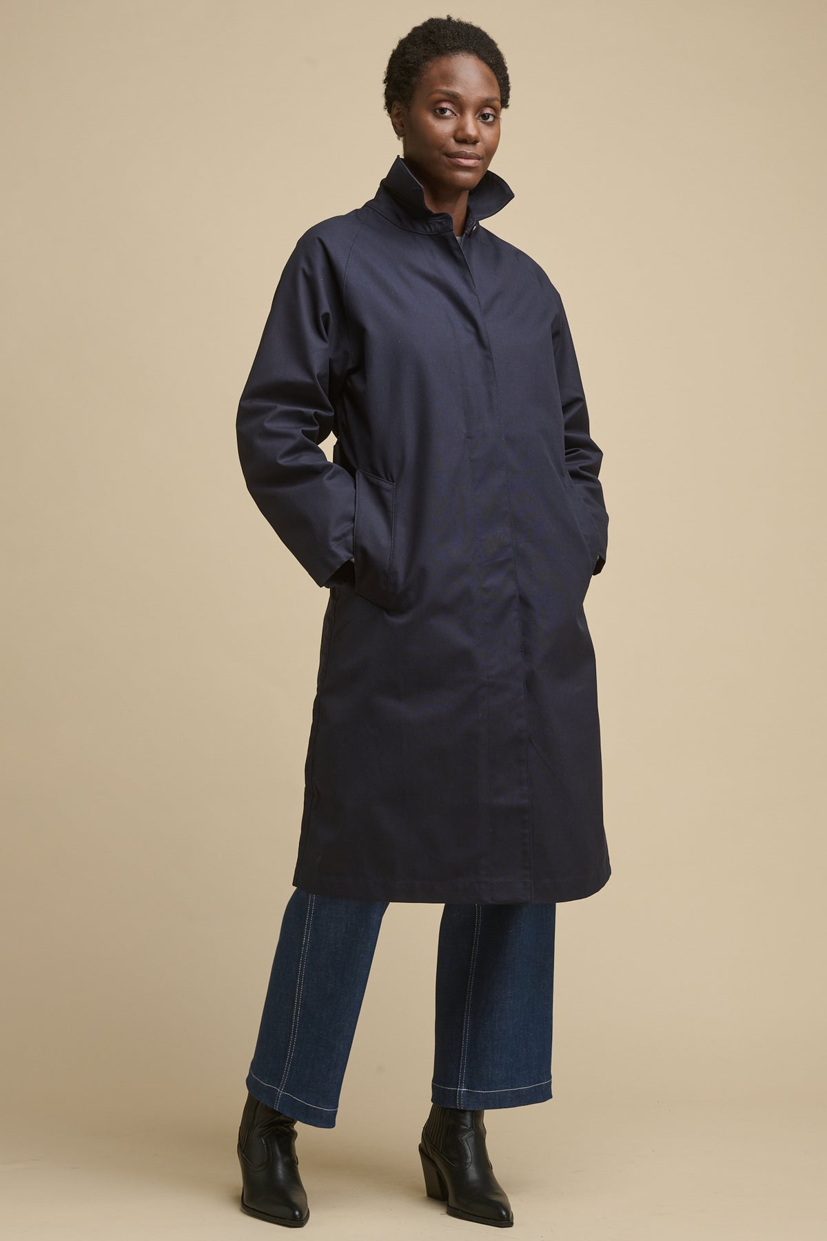 
            Full body image of female wearing women&#39;s Frances Raglan Belted Raincoat in navy with hands in two front pockets