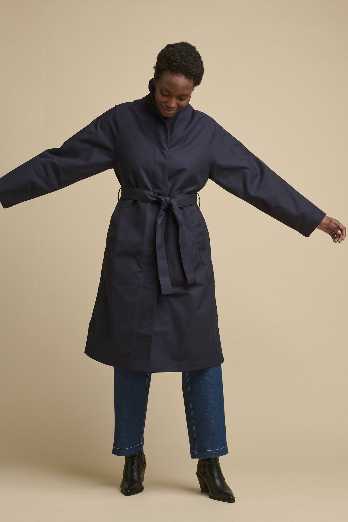 
            Full body image of female wearing women&#39;s Frances Raglan Belted Raincoat in navy with belt tie fastened around the waist 