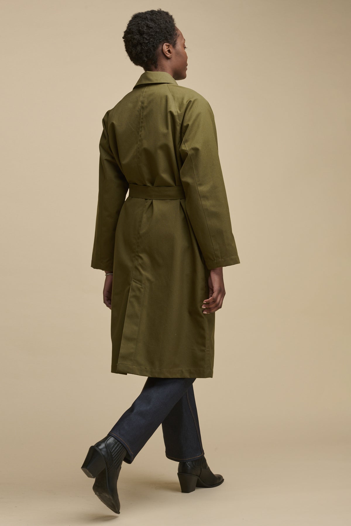 Full body image of the back of female wearing Frances Raglan Belted Raincoat in olive