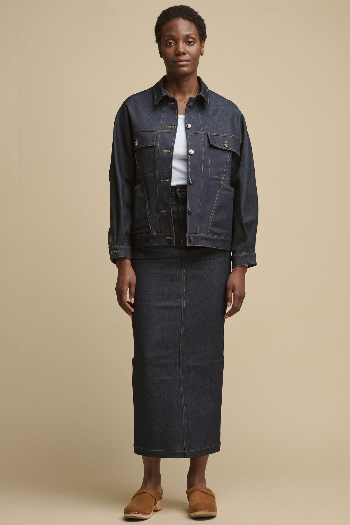 
            Full body image of black female wearing Frankie denim maxi skirt in indigo with the matching denim jacket, over racer back vest in white