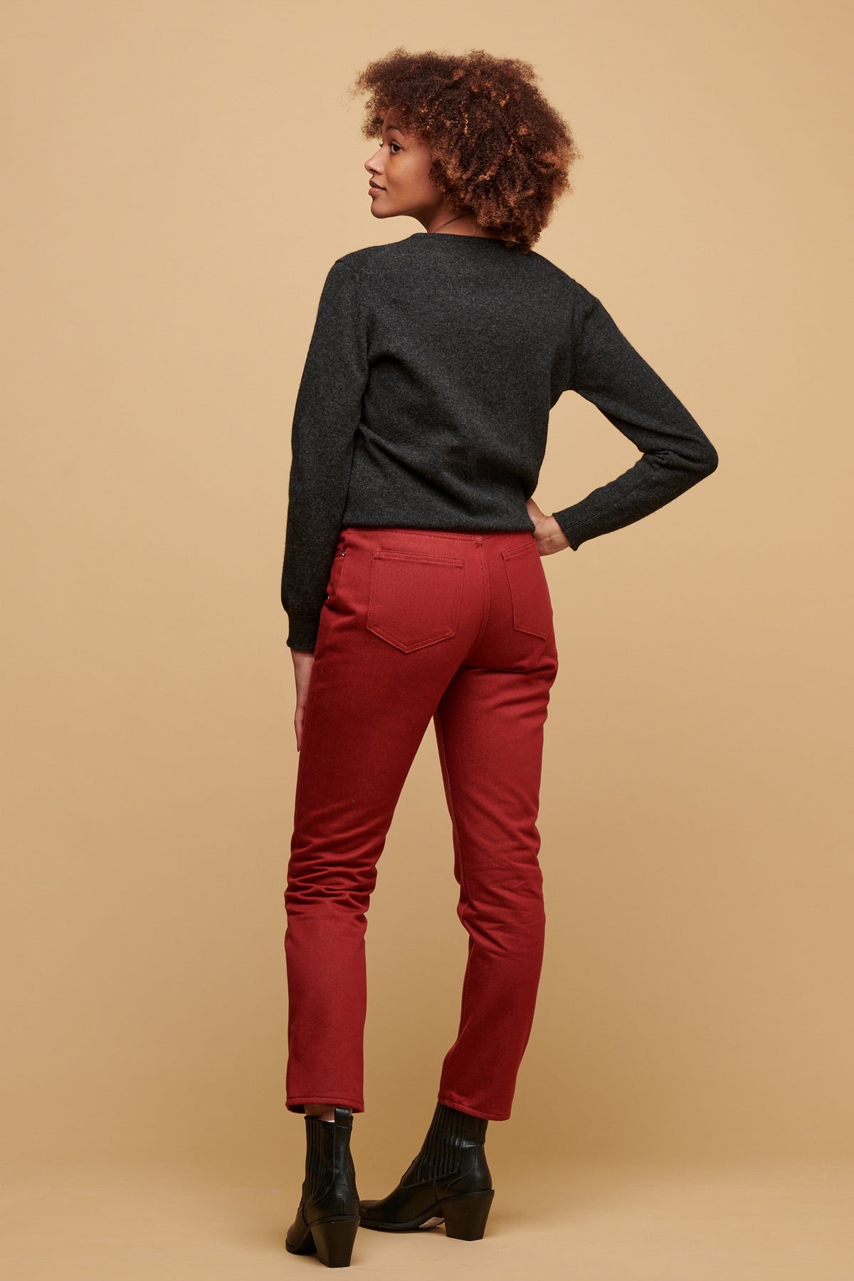 The back of female wearing Gloria jean in burgundy paired with lambswool crew neck in charcoal and a black boot.
