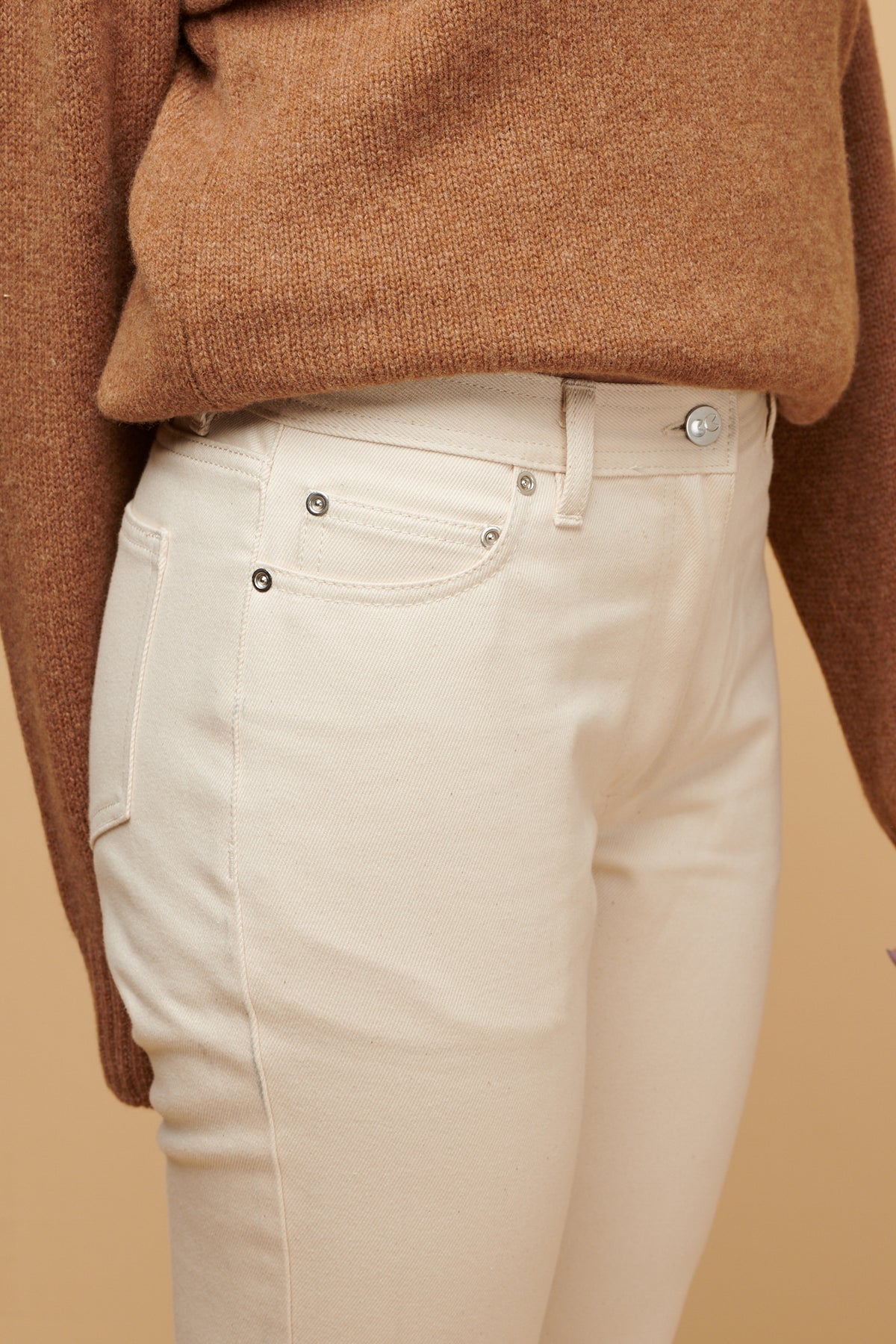 Close up of the front of Gloria jean in ecru, silver rivet details and CC logo button fastening, three front pockets including coin pocket.