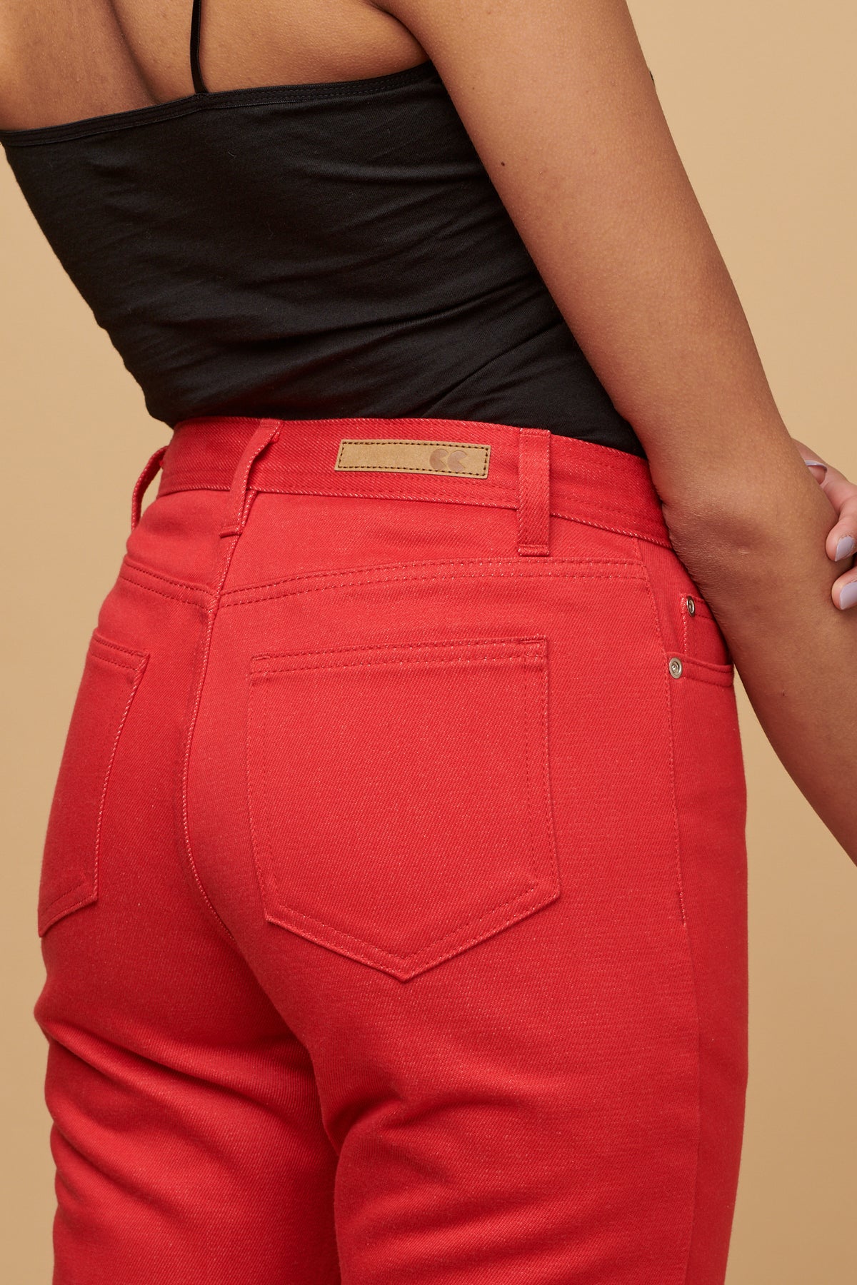 Close up of the back of female wearing Gloria jean in poppy, two back pockets and CC logo jeans patch on the waistband with beltloops.