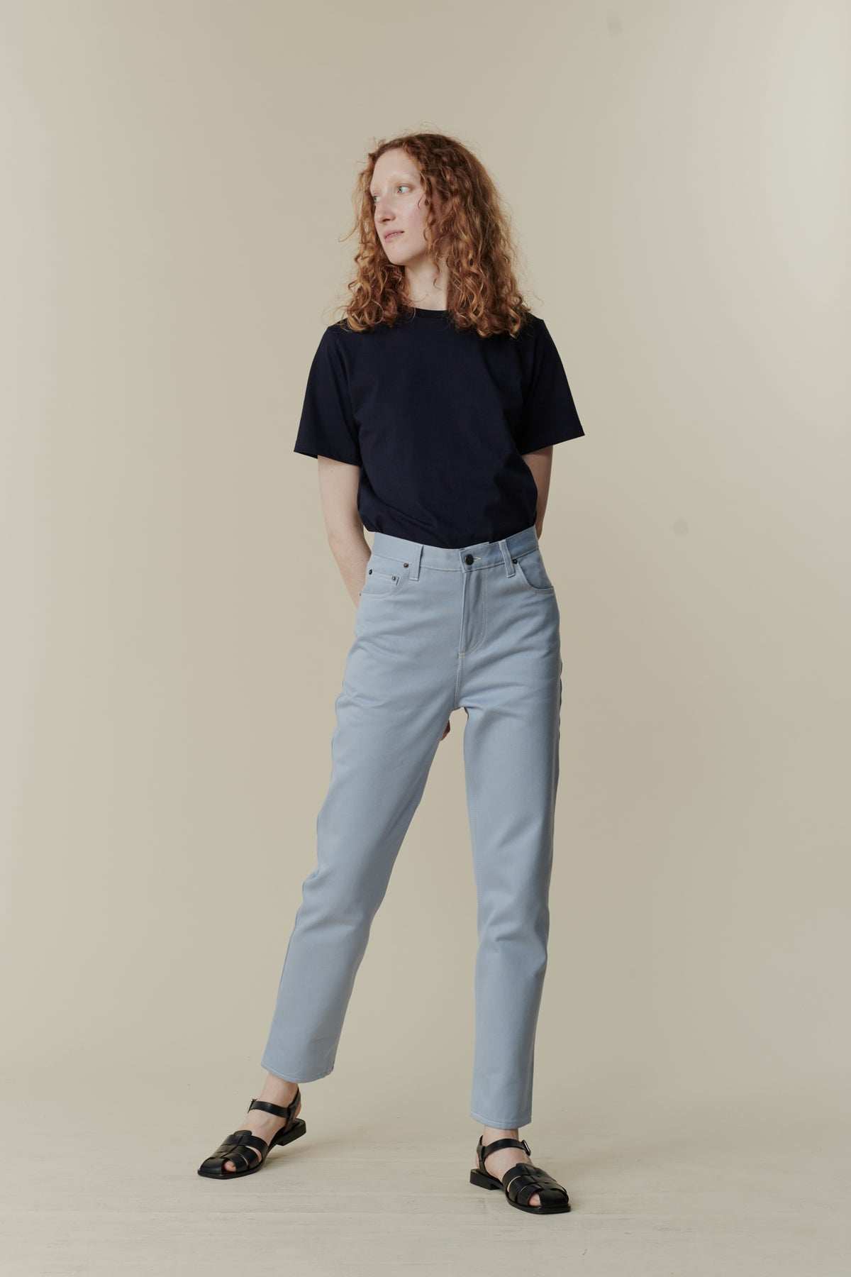 
            White female with curly ginger shoulder length hair wearing Community Clothing Gloria tapered jeans in light blue paired with navy short sleeve t shirt tucked in