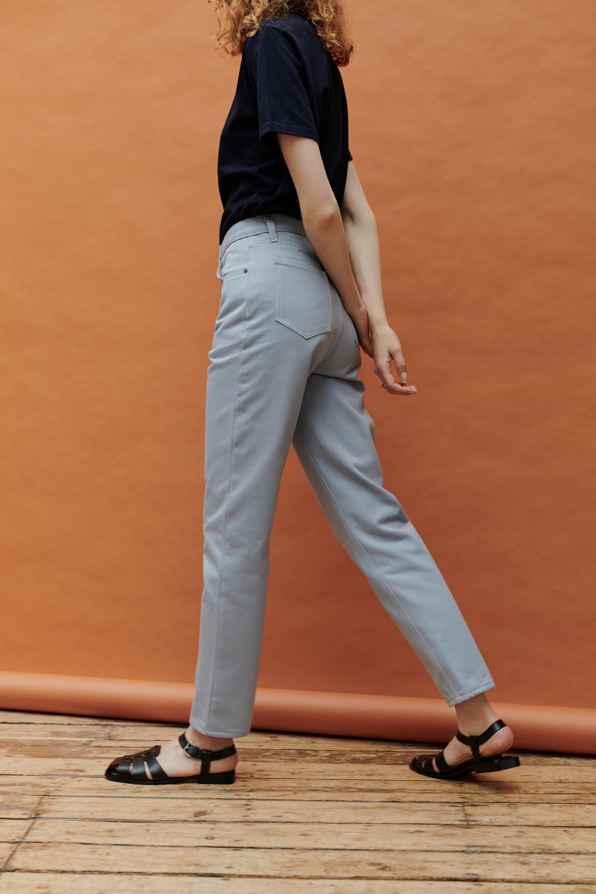 
            White female with curly ginger shoulder length hair wearing Community Clothing Gloria tapered jeans in light blue paired with navy short sleeve t shirt tucked in