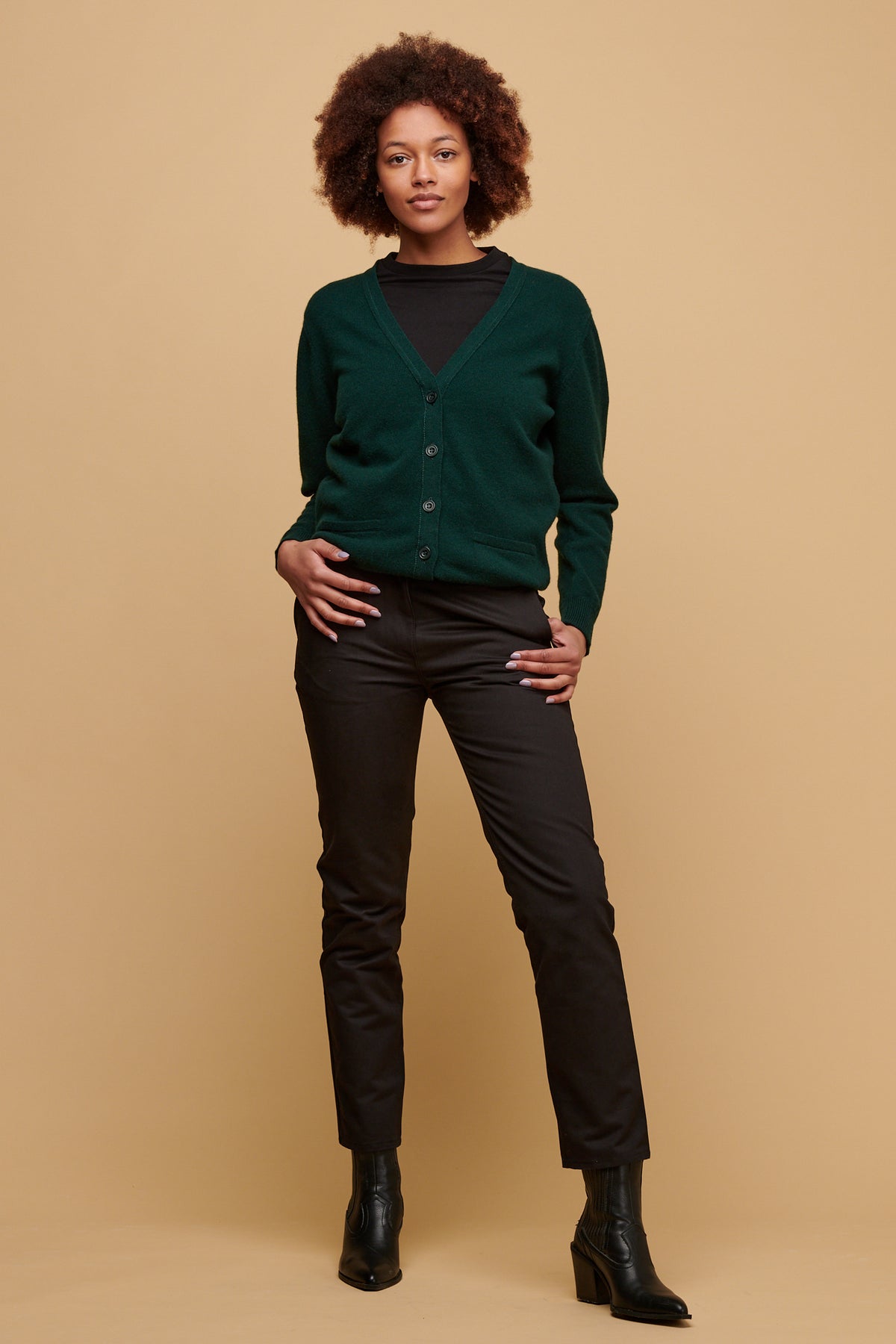 Front of female wearing heavyweight slim chino in black paired with bottle green cardigan and black boots.