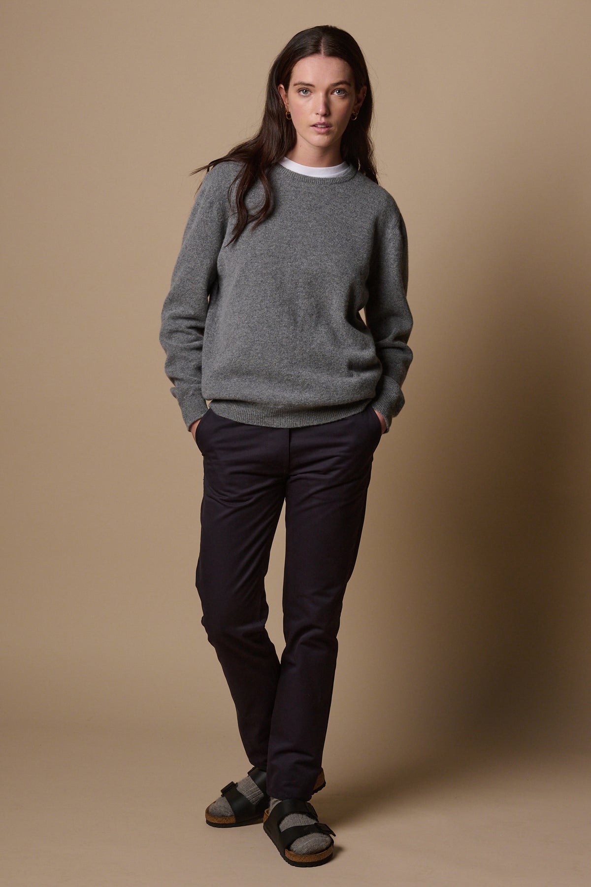 Full body image of female wearing heavyweight slim chinos in navy paired with lambswool crew neck jumper in grey