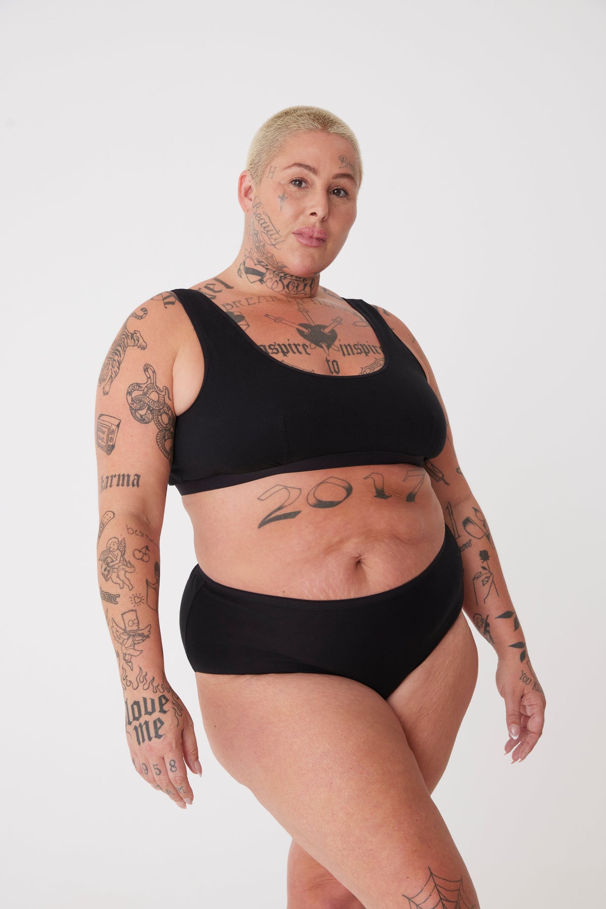 
            tattooed, plus size, white female in black high rise brief paired with black jersey bralette 