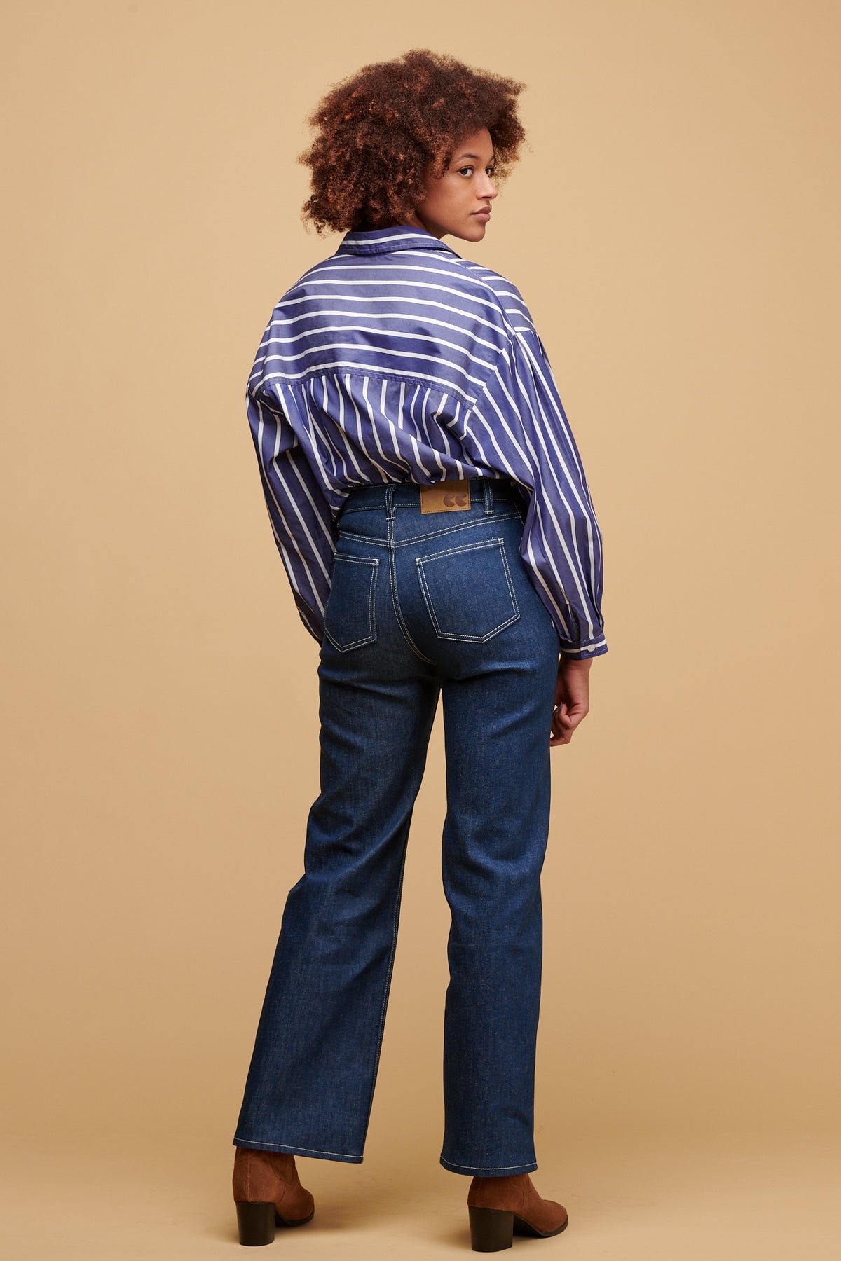 The back of female wearing high rise wide leg jean in blue with Esme shirt in blue and white stripe tucked in