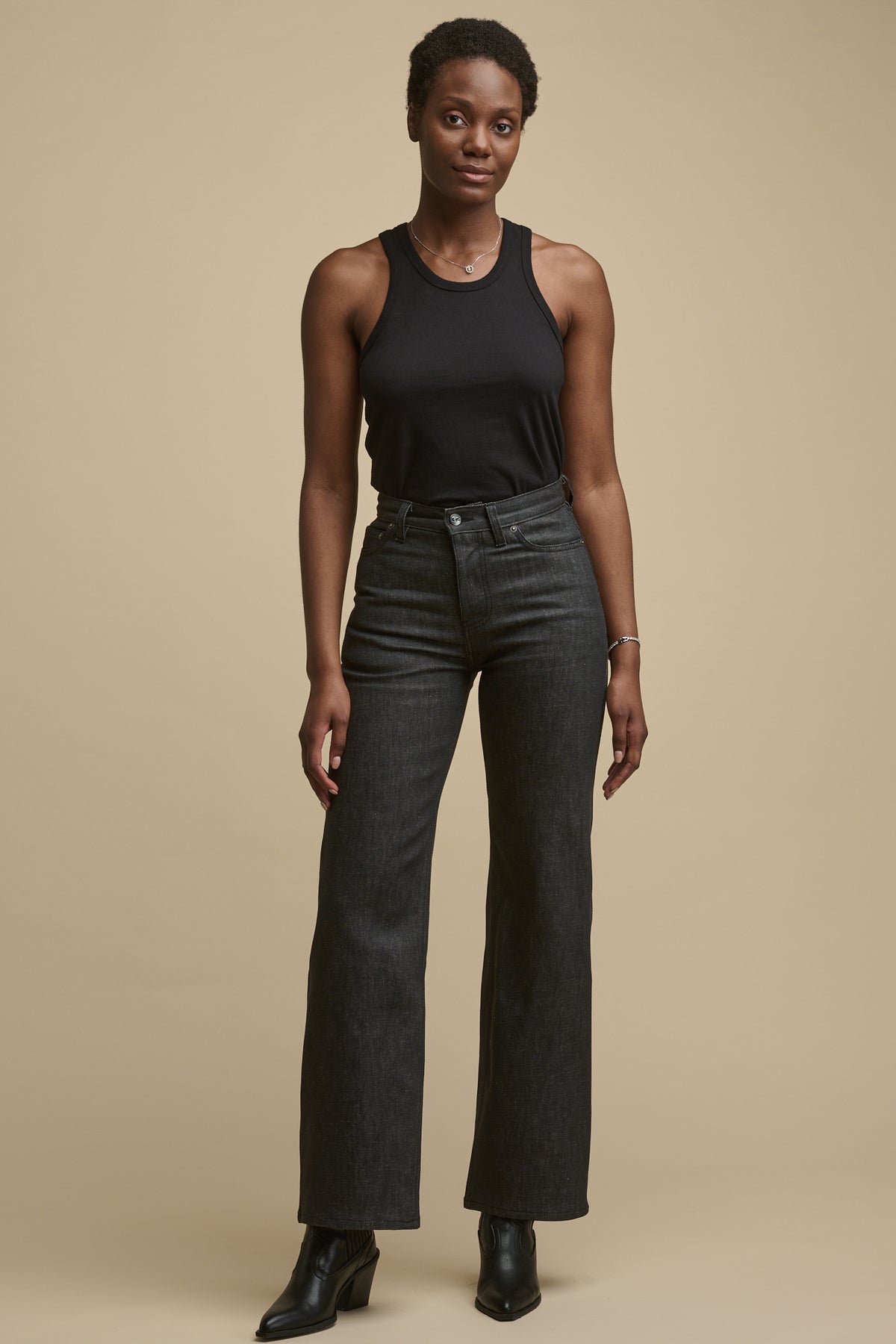Female wearing high rise wide leg jeans in black with racer back vest in black tucked in.
