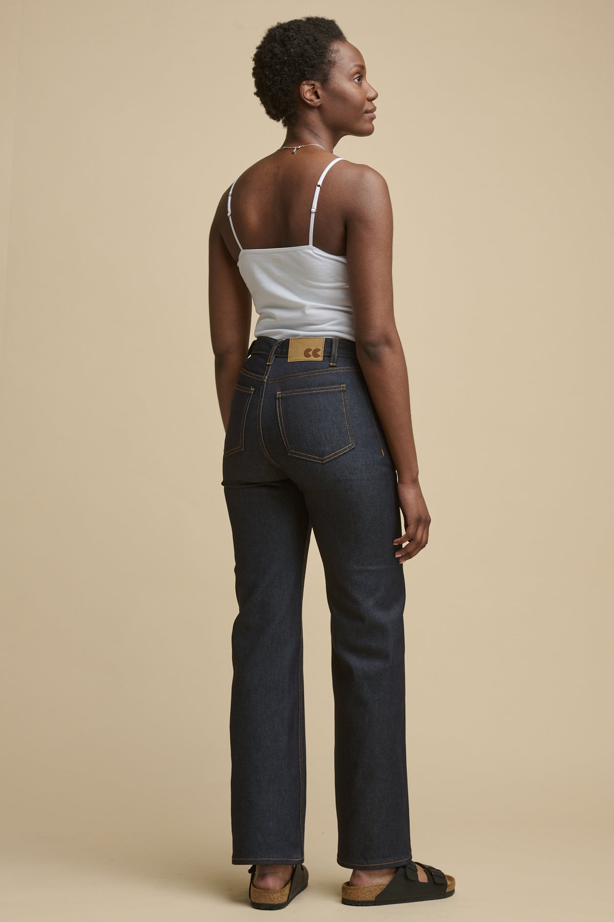 
            Full body image of the back of female wearing high rise wide leg jeans in indigo denim with brown jeans patch with CC logo on the back