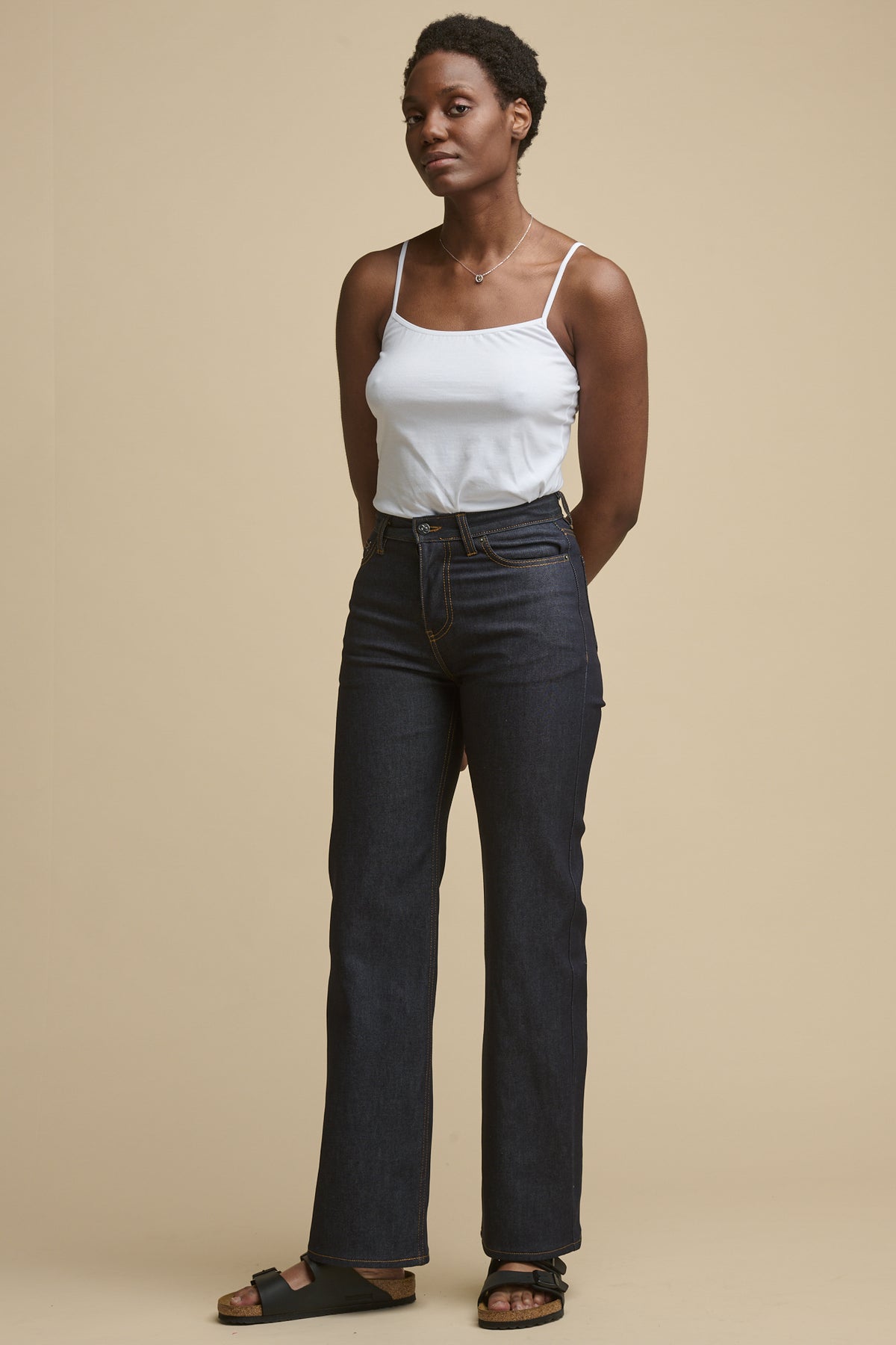 
            Full body image of female wearing high rise wide leg jeans in indigo paired with white camisole. 