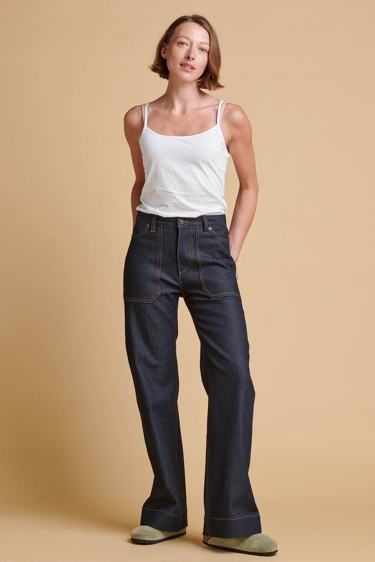 Woman wearing indigo jeans and white camisole.