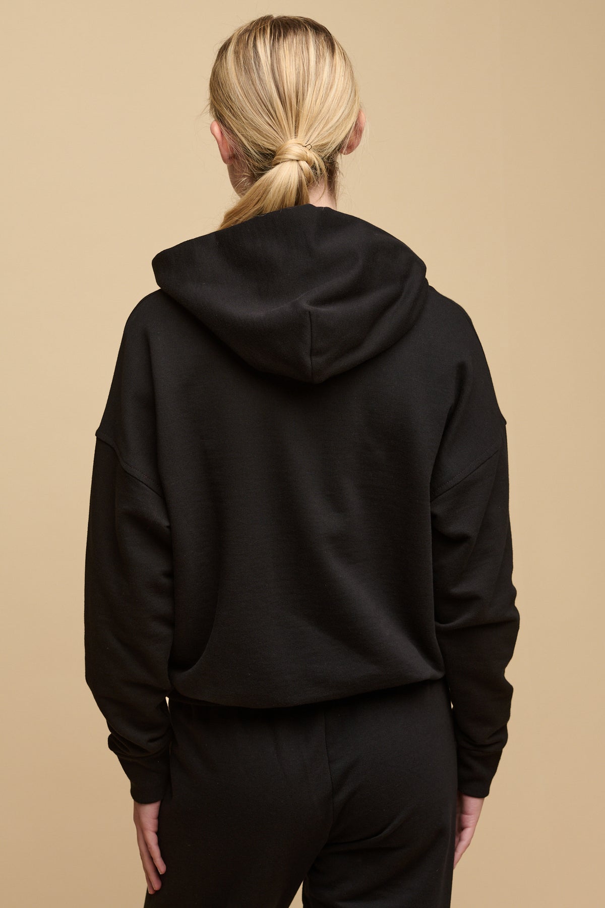 The back of female wearing hooded sweatshirt in black