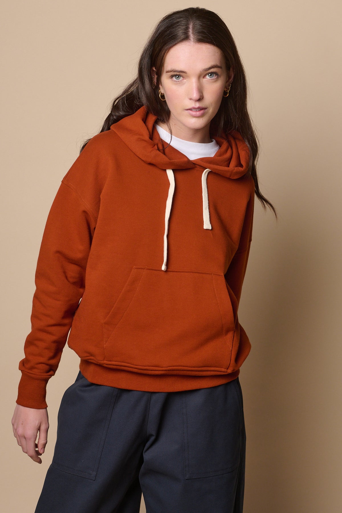 Thigh up image of female wearing hooded sweatshirt in cinnamon