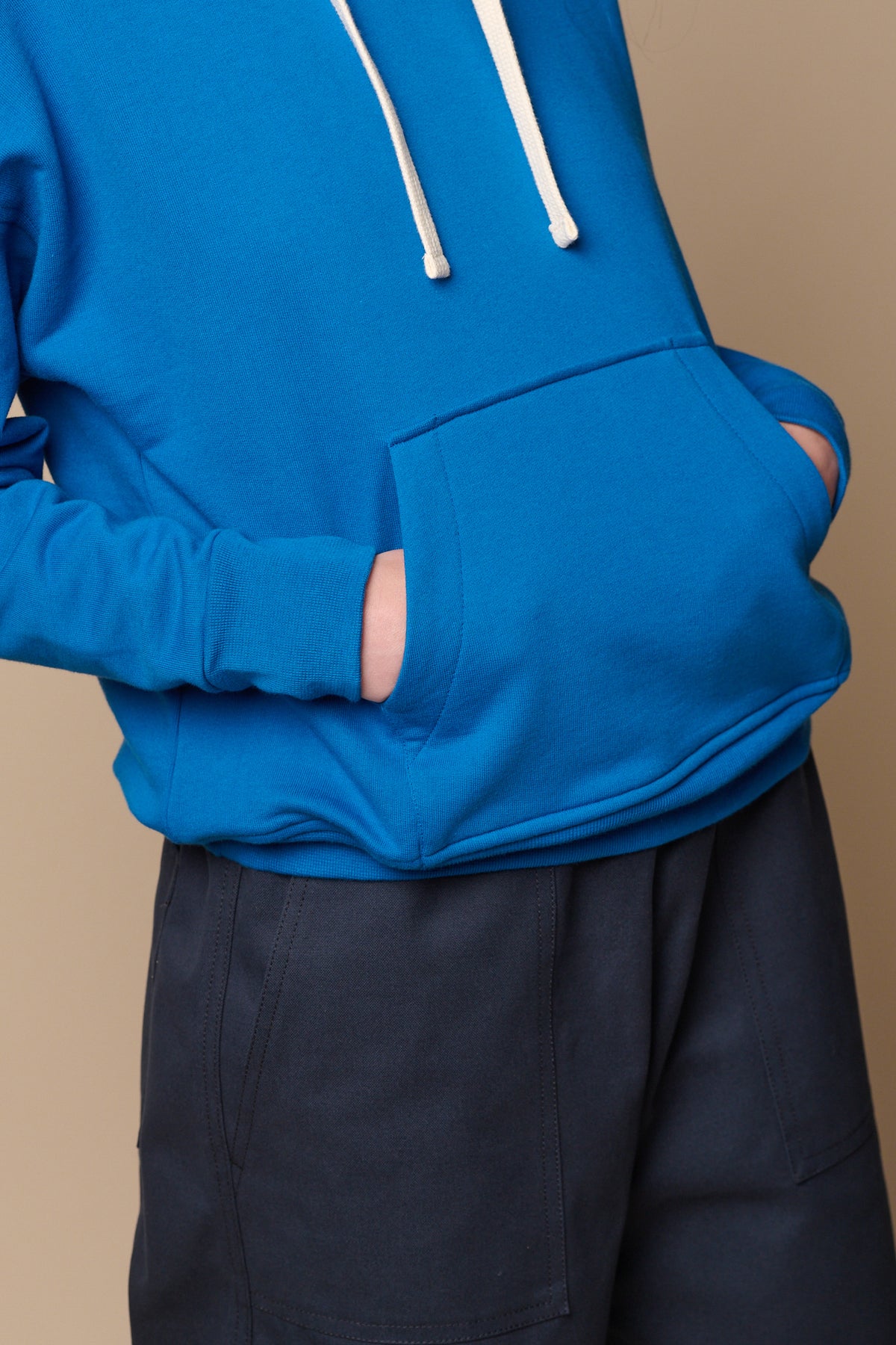 ecru drawcord detail of the hood, model has both hands in large, front central pocket