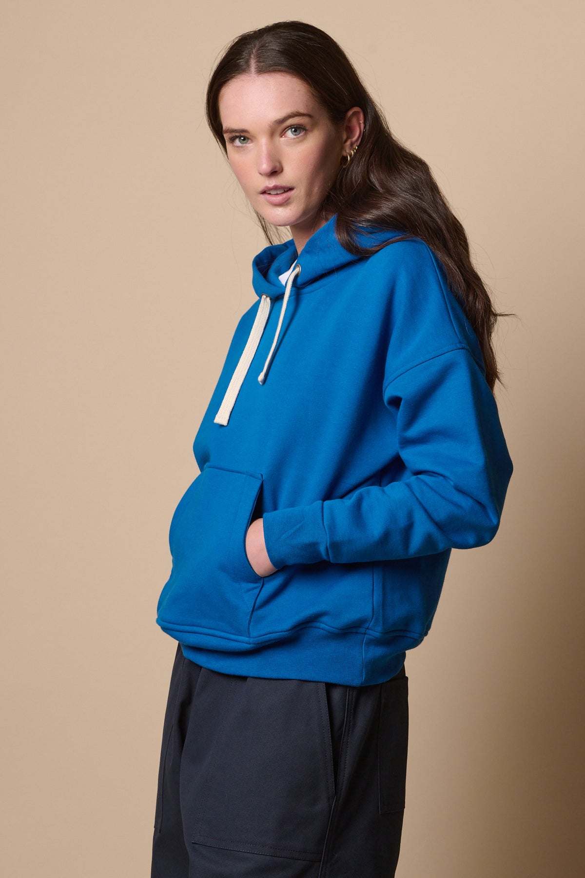 
            female from the side wearing hooded sweatshirt in coablt with one hand in front central pocket