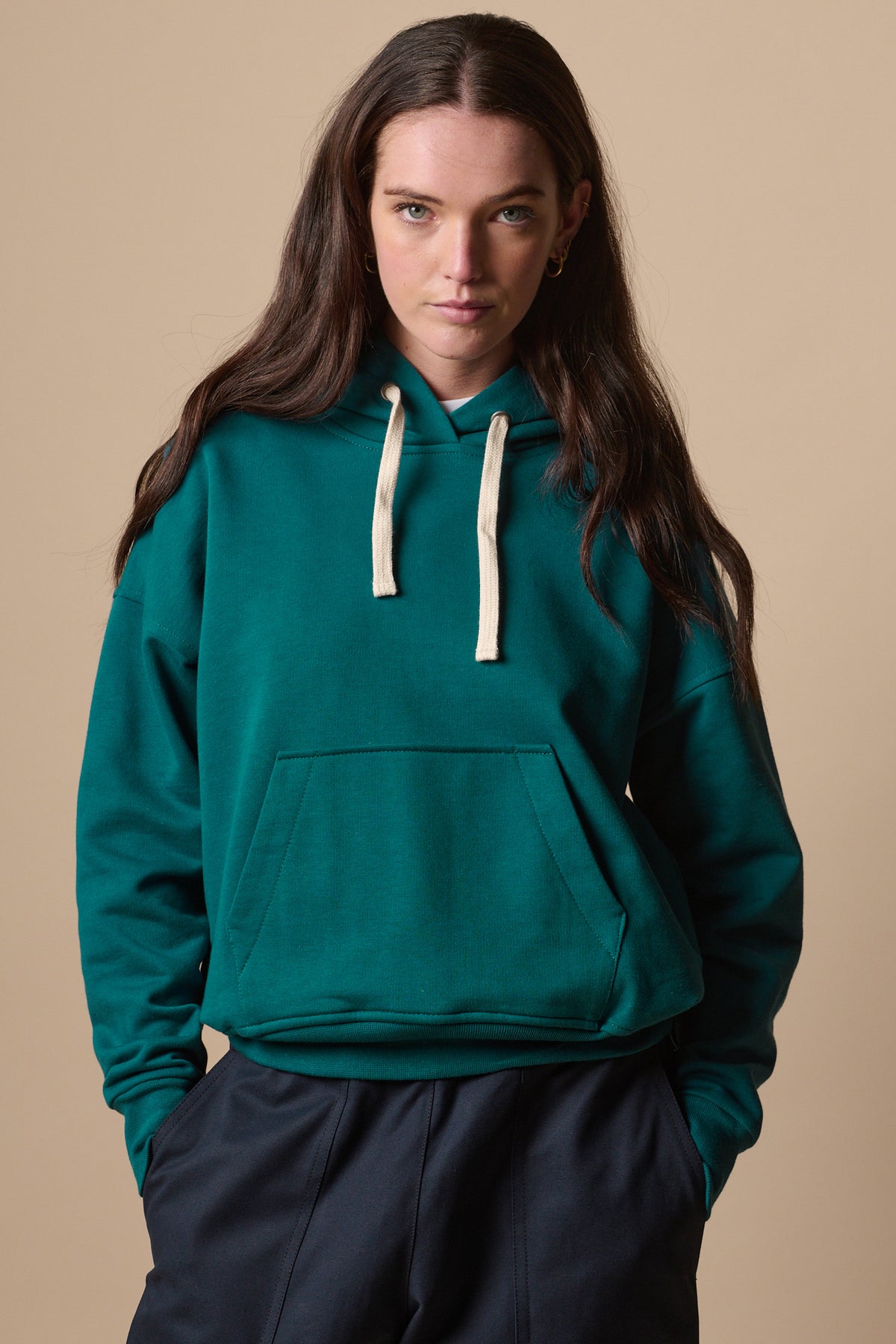 Thigh up image of white female wearing hooded sweatshirt in teal