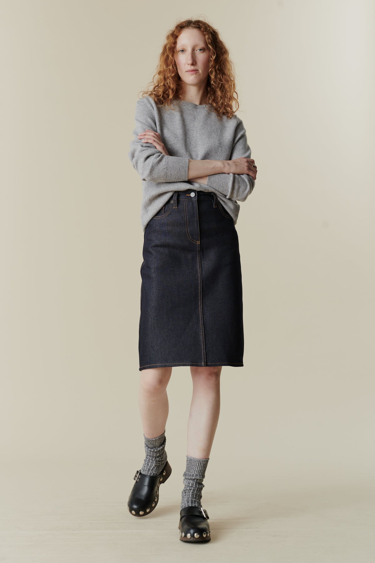 Female wearing knee length jean skirt in indigo denim.