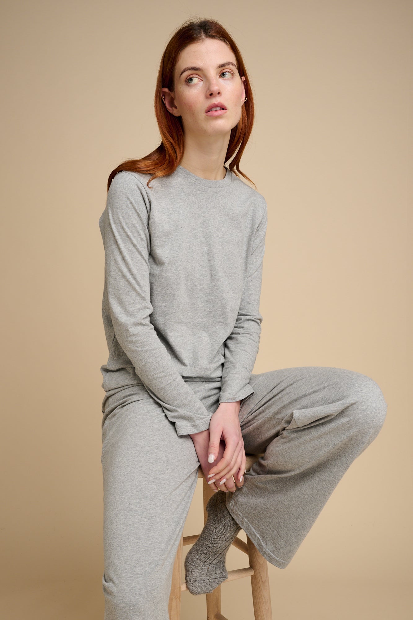Woman sat on stool wearing grey marl pyjama set.