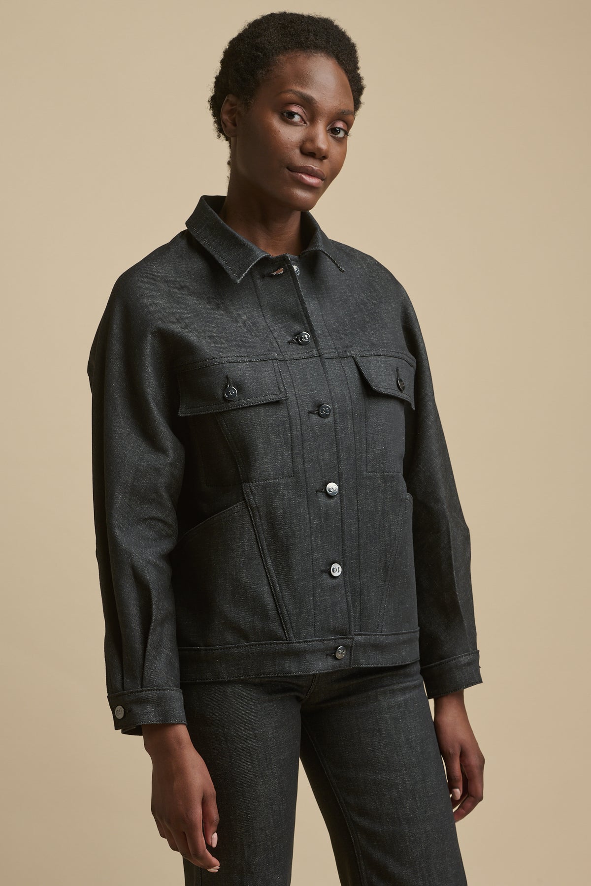 
            Thigh up front of female wearing Jodie denim jacket in black with front buttons fastened, CC logo buttons