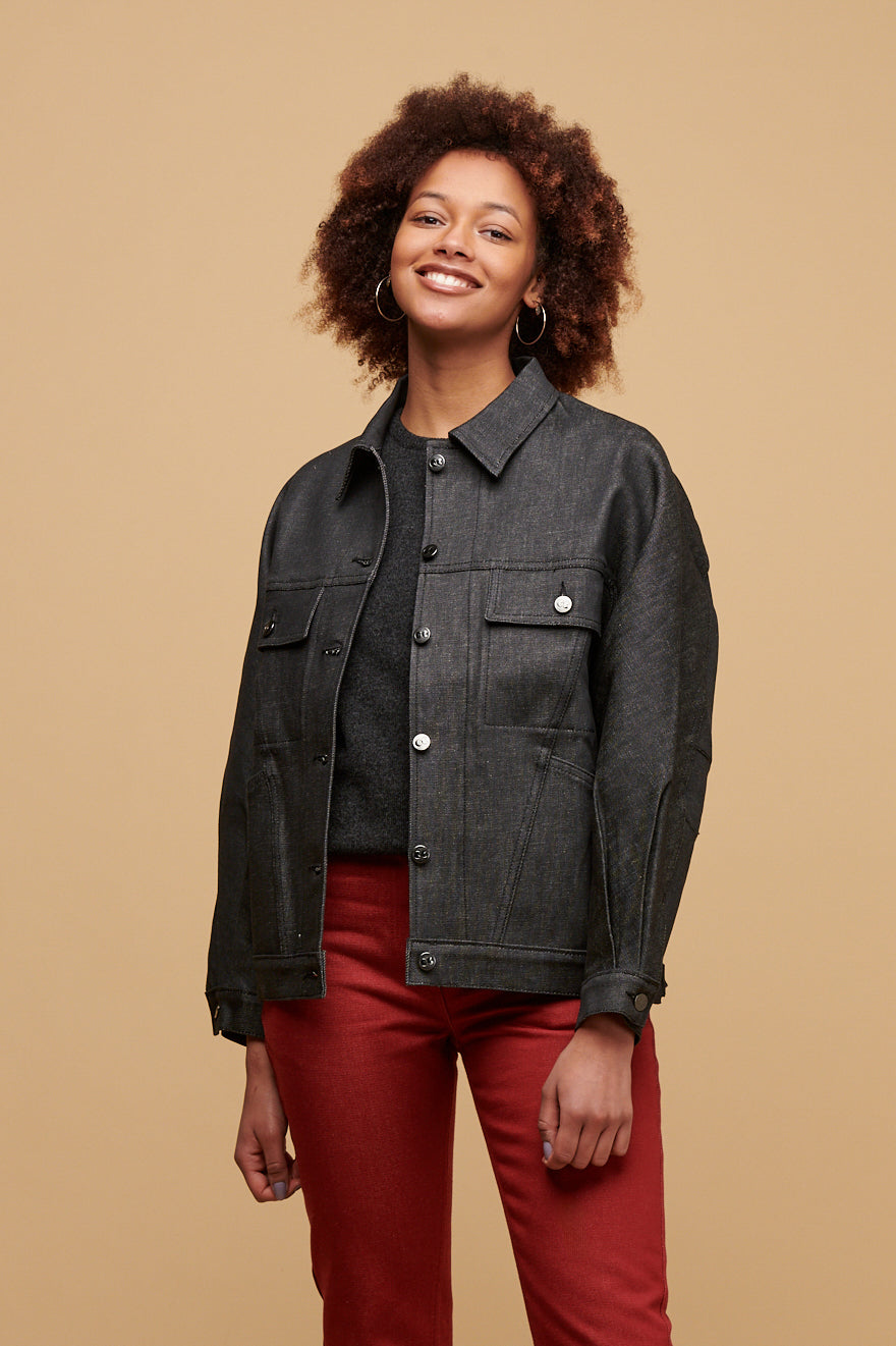 Thigh up of smiley black female wearing Jodie jacket in black unbuttoned over lambswool crew neck in charcoal paired with Gloria jean in burgundy