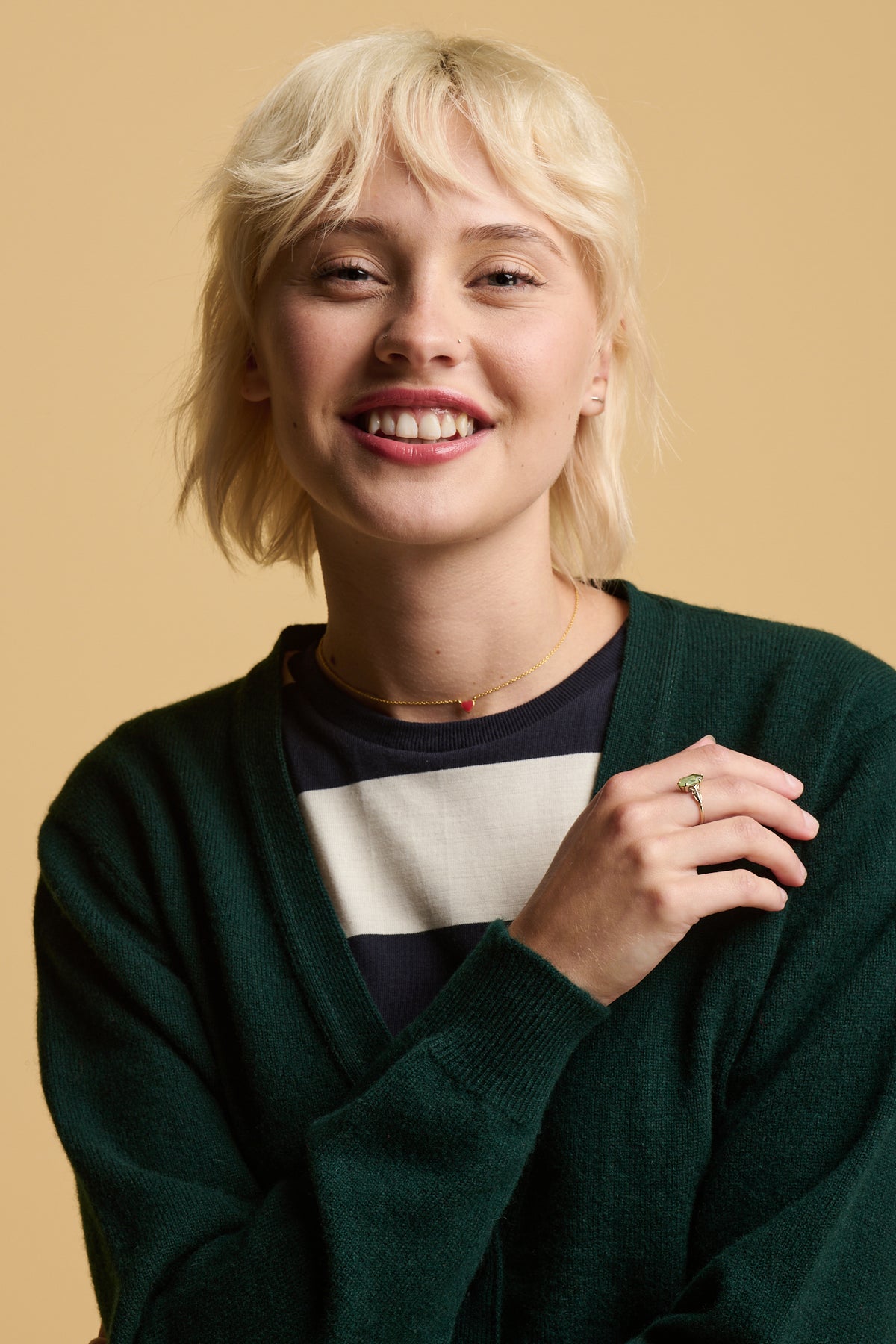 
            Portrait of smiley female with blonde hair wearing lambswool cardigan in bottle green worn over wide stripe t shirt in ecru navy