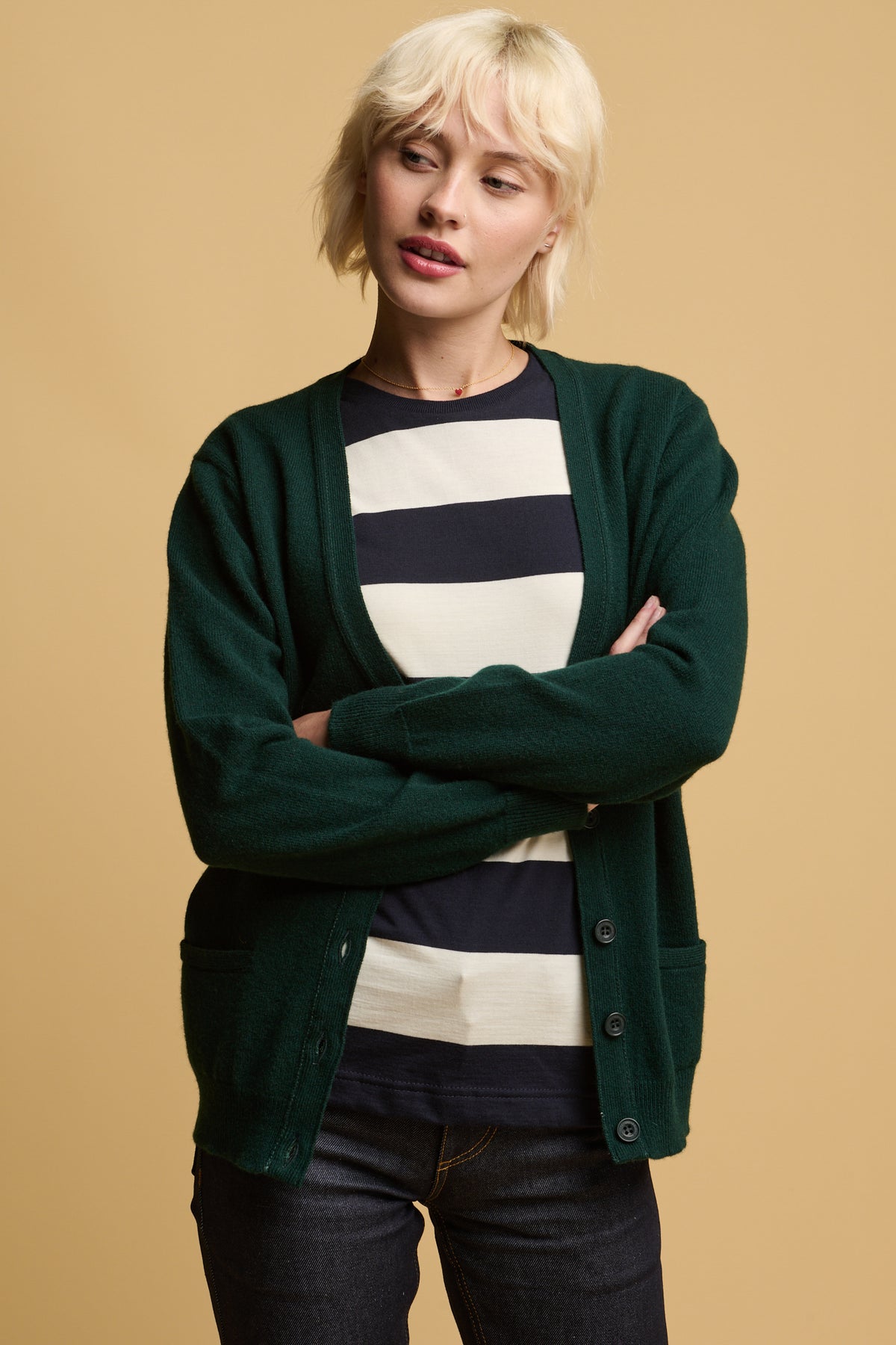 
            Thigh up of female with her arms folded wearing unbuttoned lambswool cardigan in bottle green over wide stripe t shirt in ecru and navy