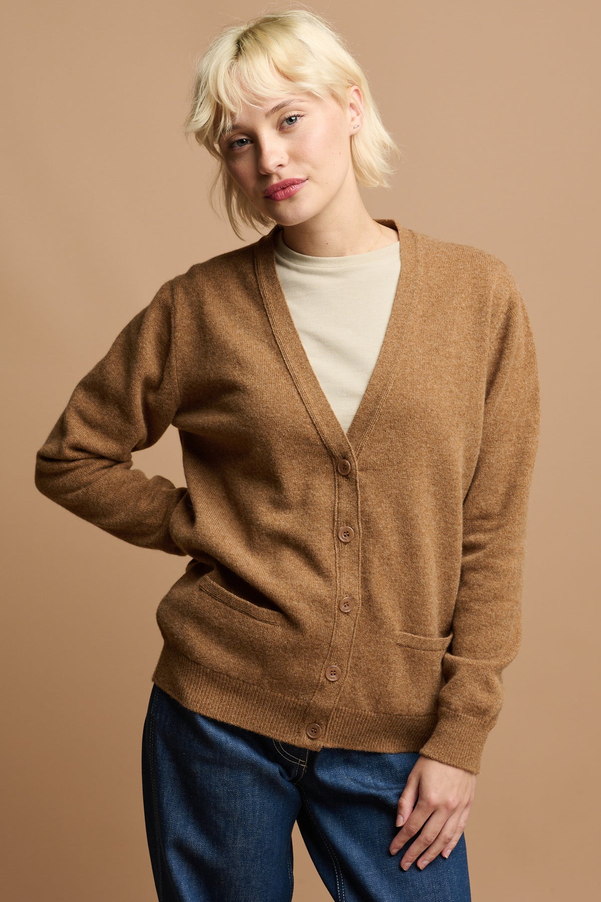 
            Female with blonde hair wearing fastened 5 button cardigan in dark camel with two front pockets 