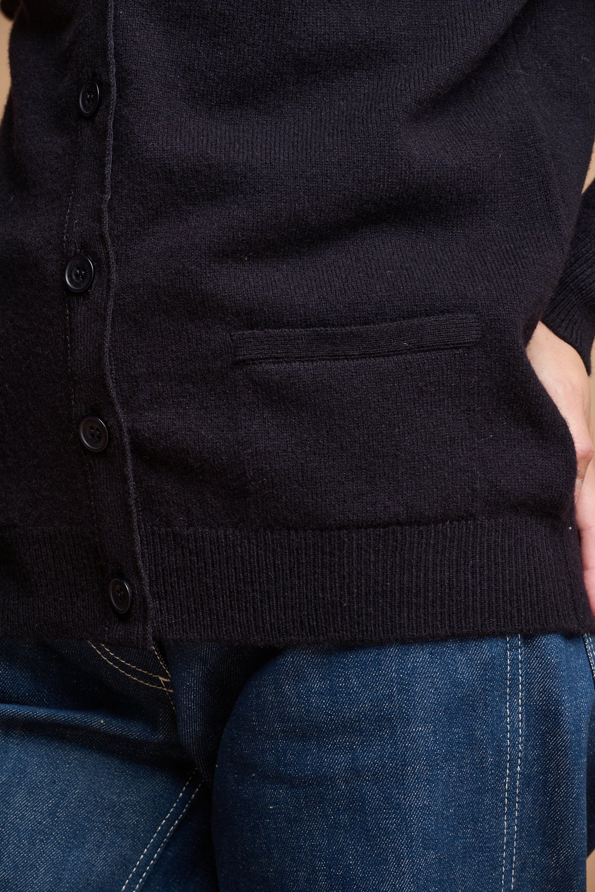 
            Close up of the front of cardigan buttoned up with two front pockets with work jeans in blue