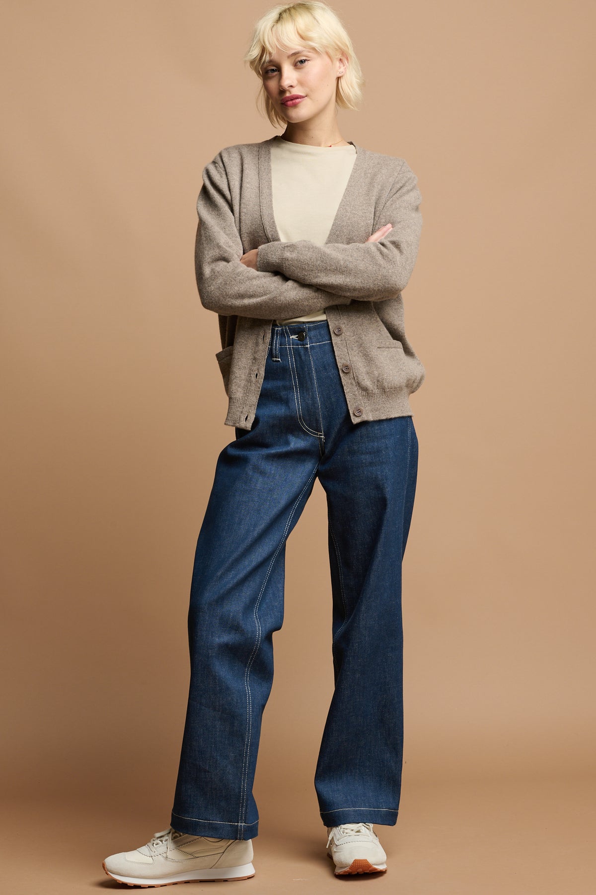Female with arms folded wearing v neck lambswool cardigan in truffle work trousers in blue