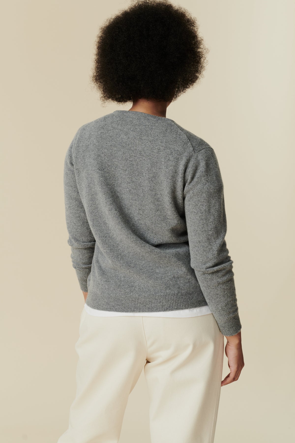 Thigh up image of female lambswool crew neck jumper in grey