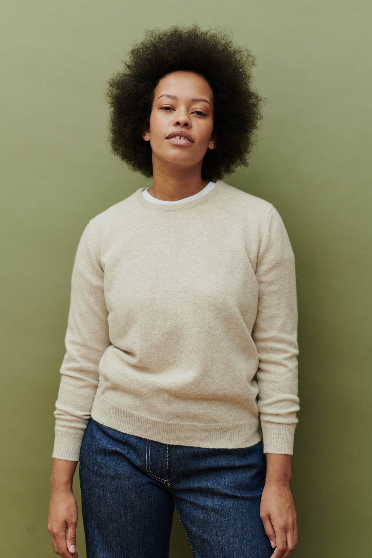 Thigh up image of female wearing lambswool crew neck jumper in linen