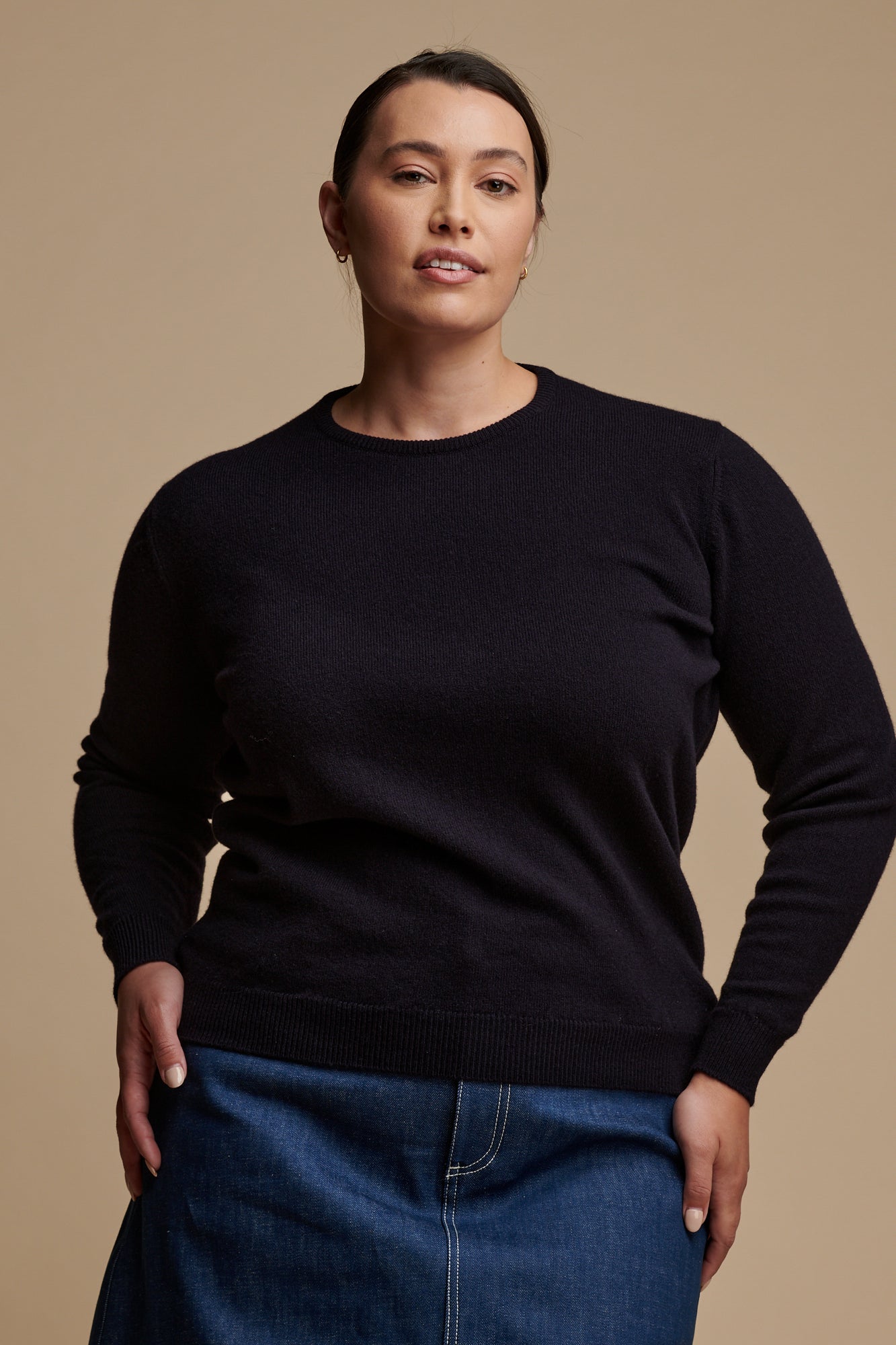 Thigh up of female wearing lambswool crew neck jumper in navy paired with Bobbie a line denim midi skirt in blue.
