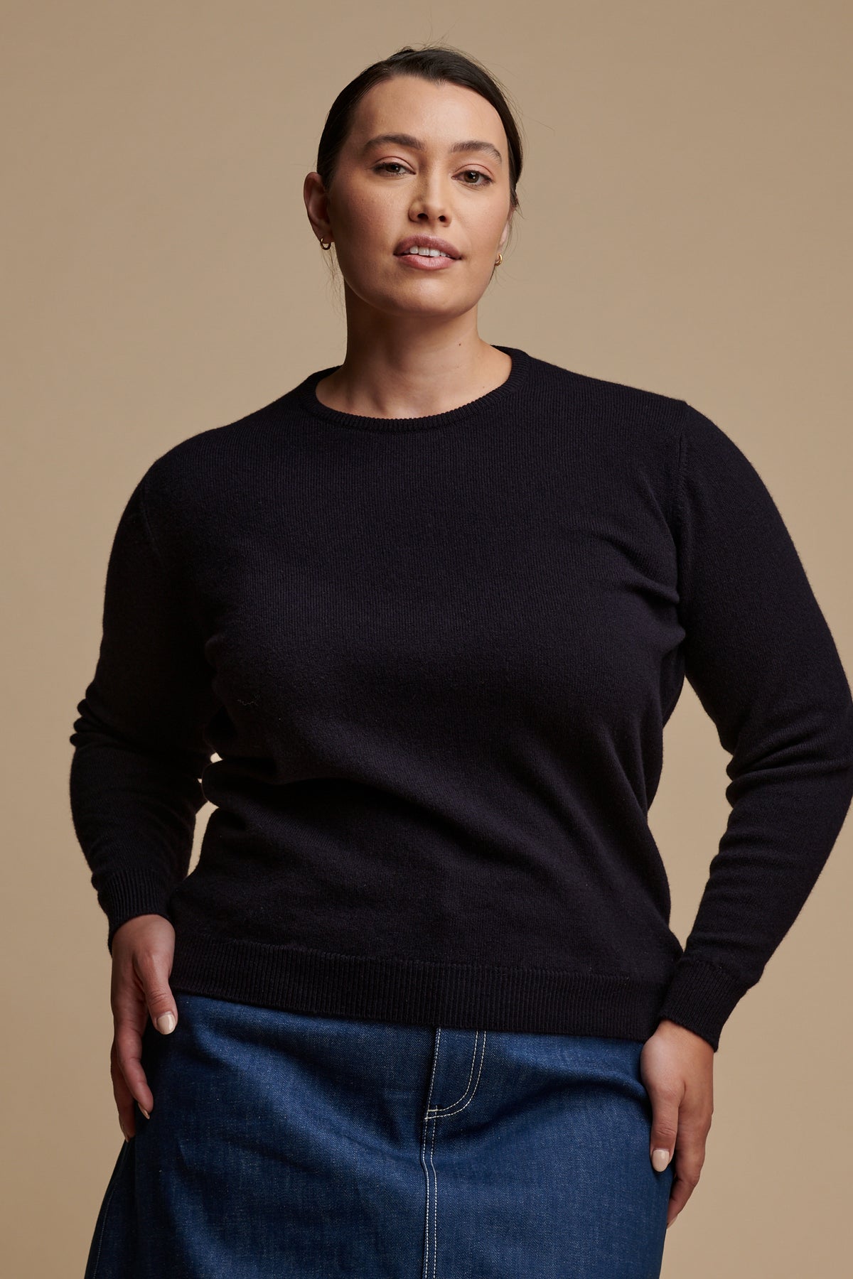 Thigh up of female wearing lambswool crew neck jumper in navy paired with Bobbie a line denim midi skirt in blue.