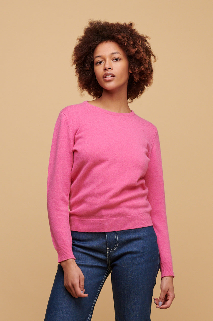 
            Black female with afro from the thigh up wearing lambswool crew neck in rose pink paired with high rise wide leg jeans