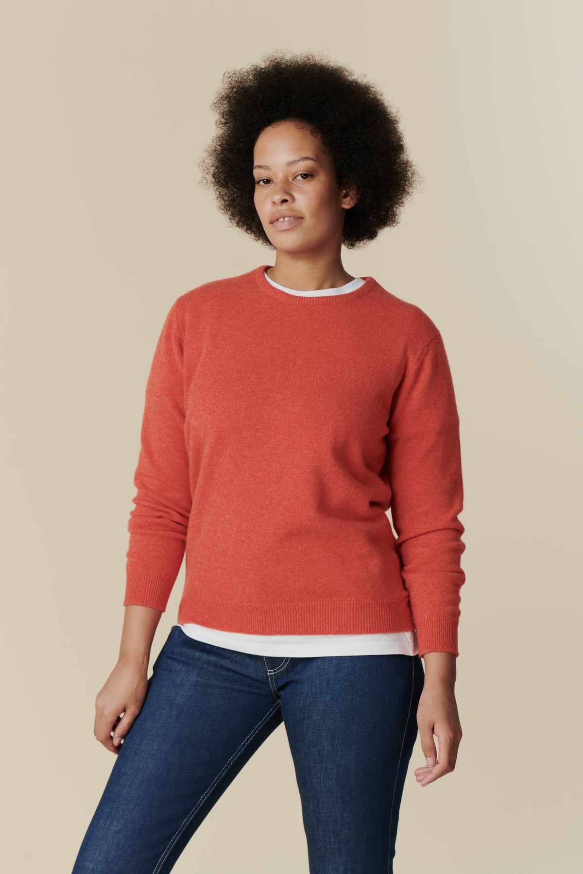 Knee up image of female wearing lambswool crew neck in flame red